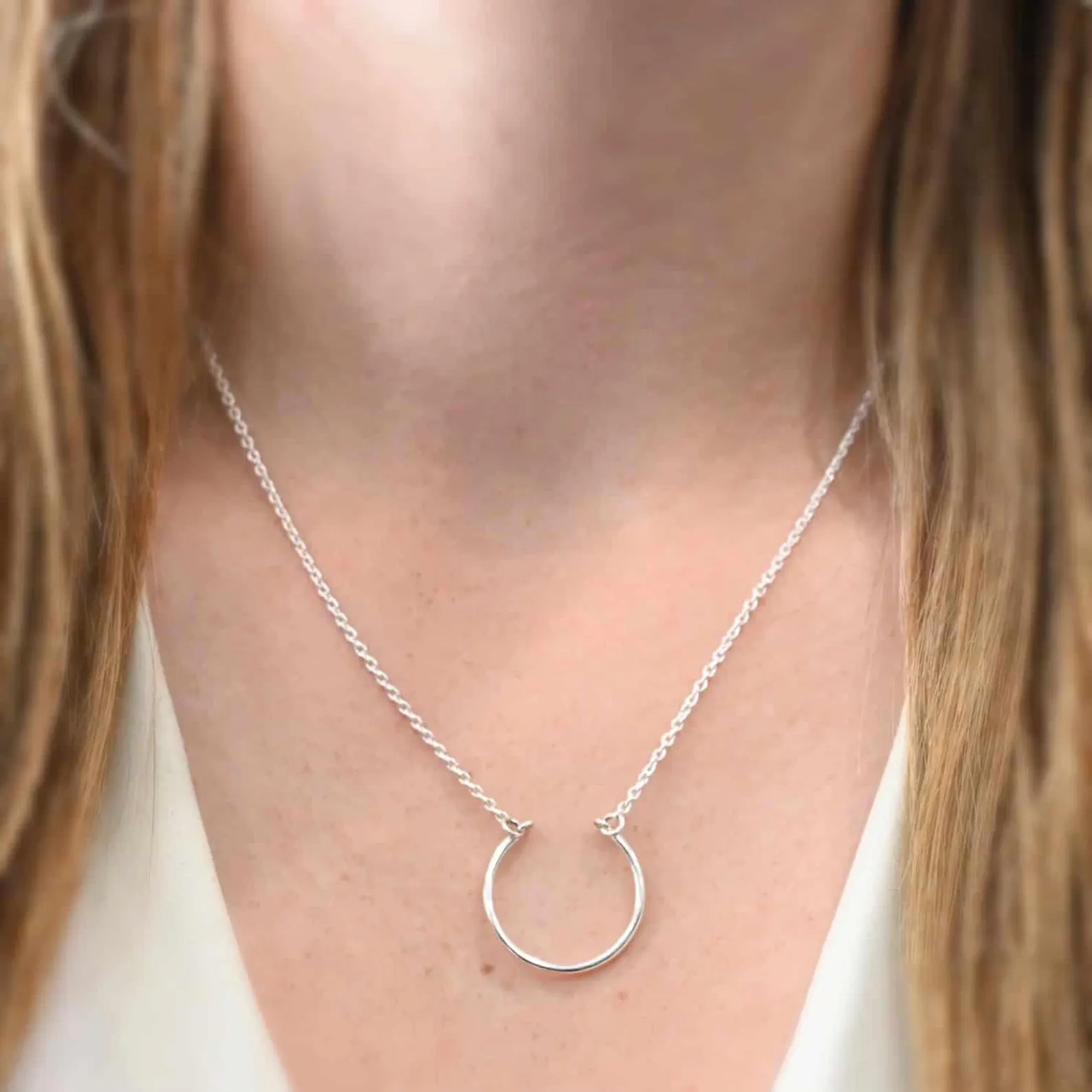 Claire Charm Necklace shown on model with white shirt and brown hair