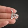 Wild Prairie Charm - shiny shown in hand - wild prairie tag, cross & angel wing charm