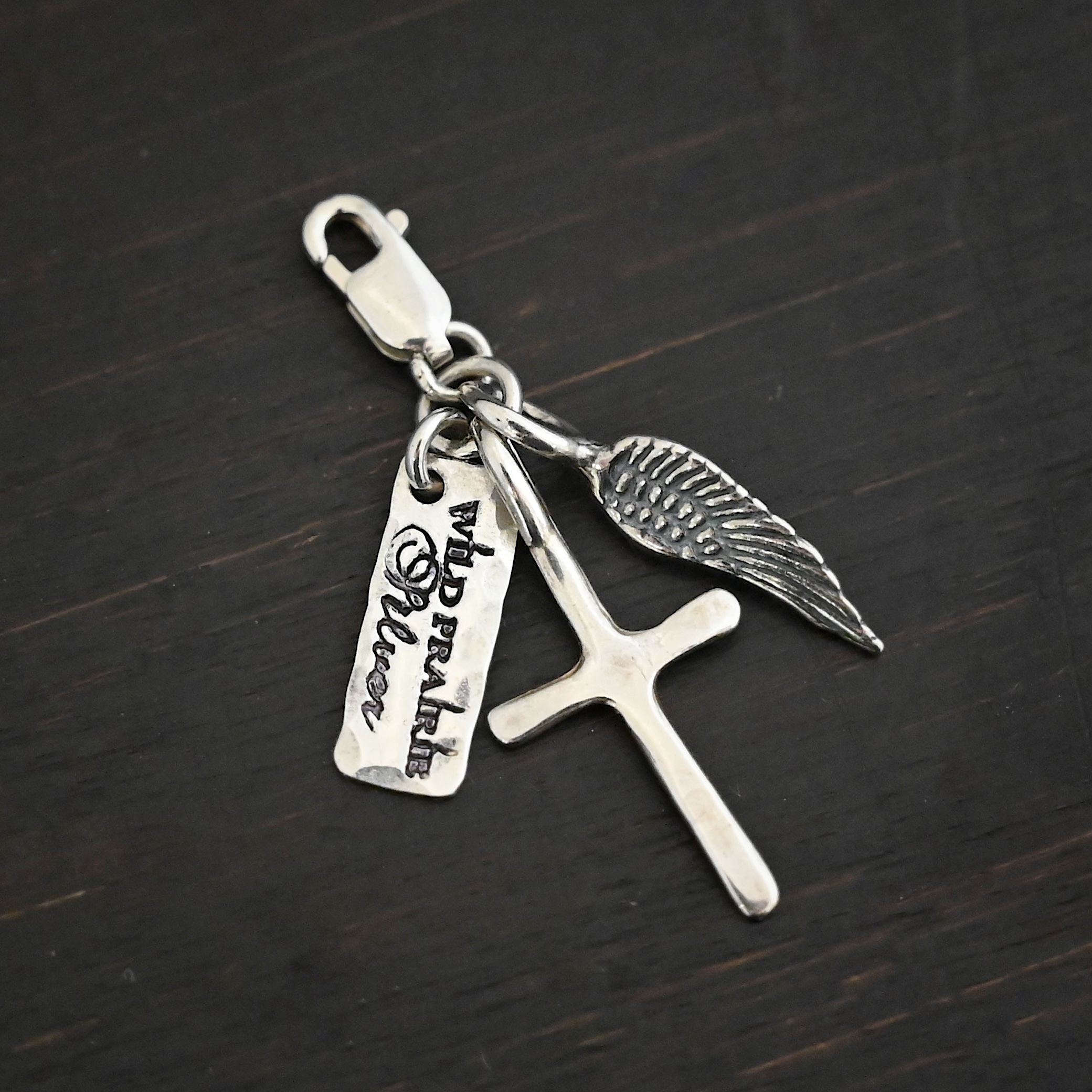 Wild Prairie Charm - shiny shown on dark background - wild prairie tag, cross & angel wing charm