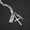 Wild Prairie Charm - shiny shown on dark background - wild prairie tag, cross & angel wing charm