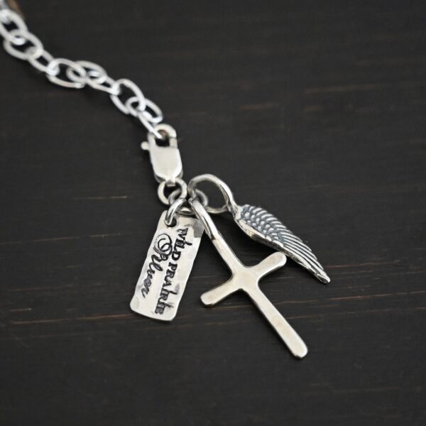 Wild Prairie Charm - shiny shown on dark background - wild prairie tag, cross & angel wing charm