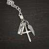 Wild Prairie Charm - shiny shown on dark background - wild prairie tag, cross & angel wing charm