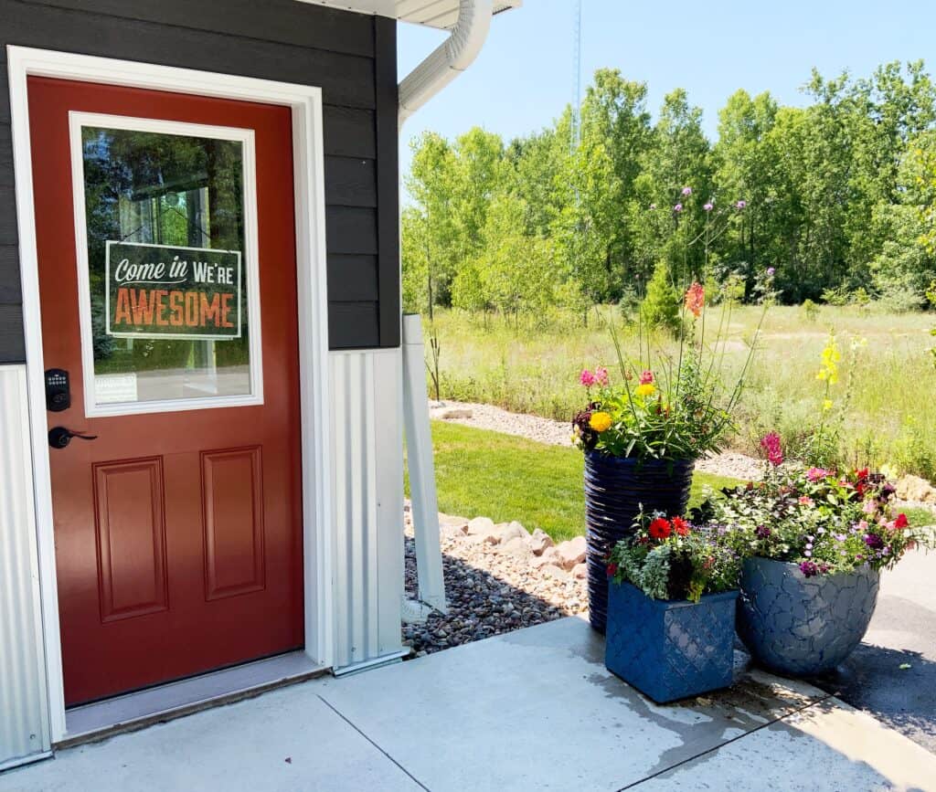 Wild Prairie Studio with flowers & sign saying "come in we're awesome" on the prairie