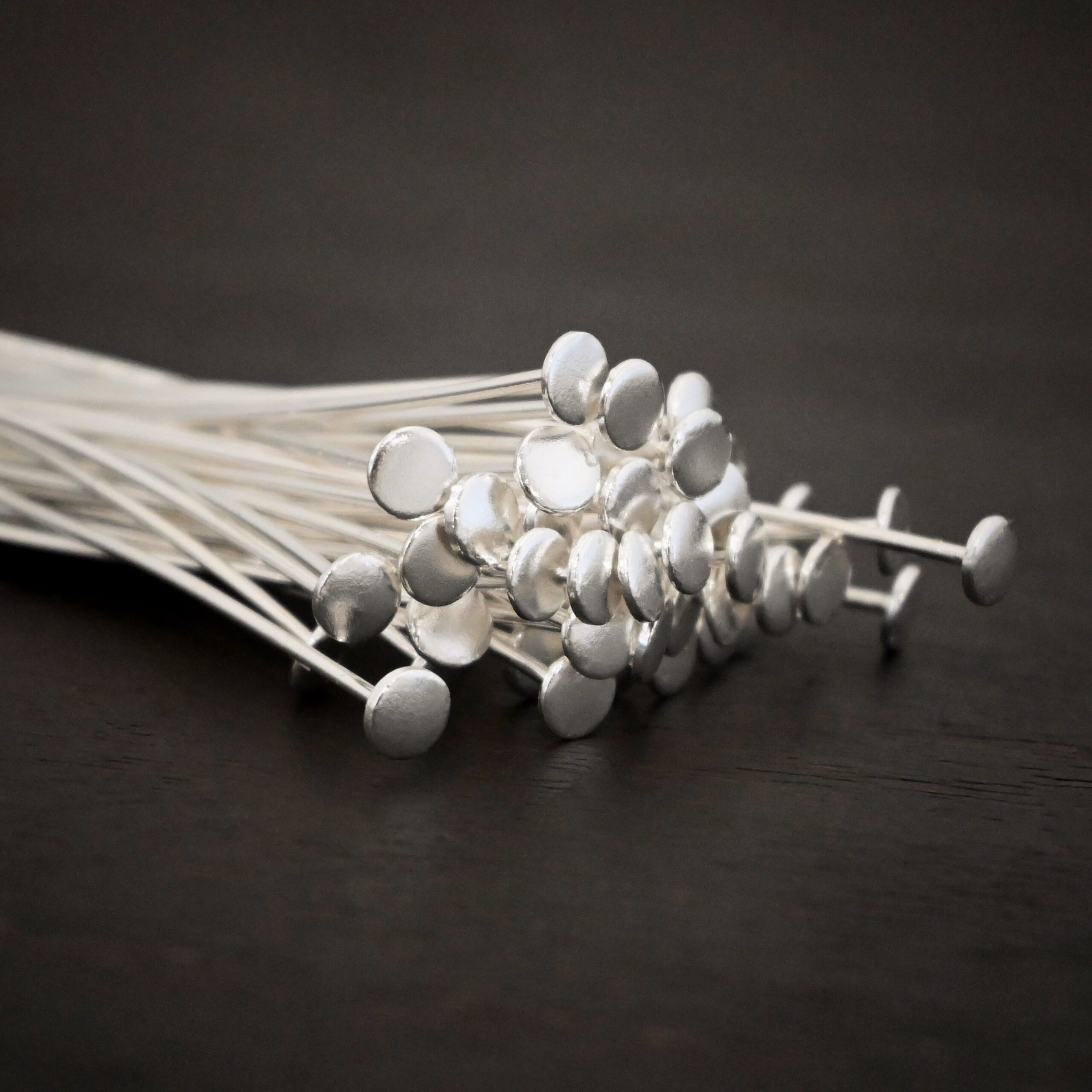 Sterling Silver Shiny nail headpins on dark background