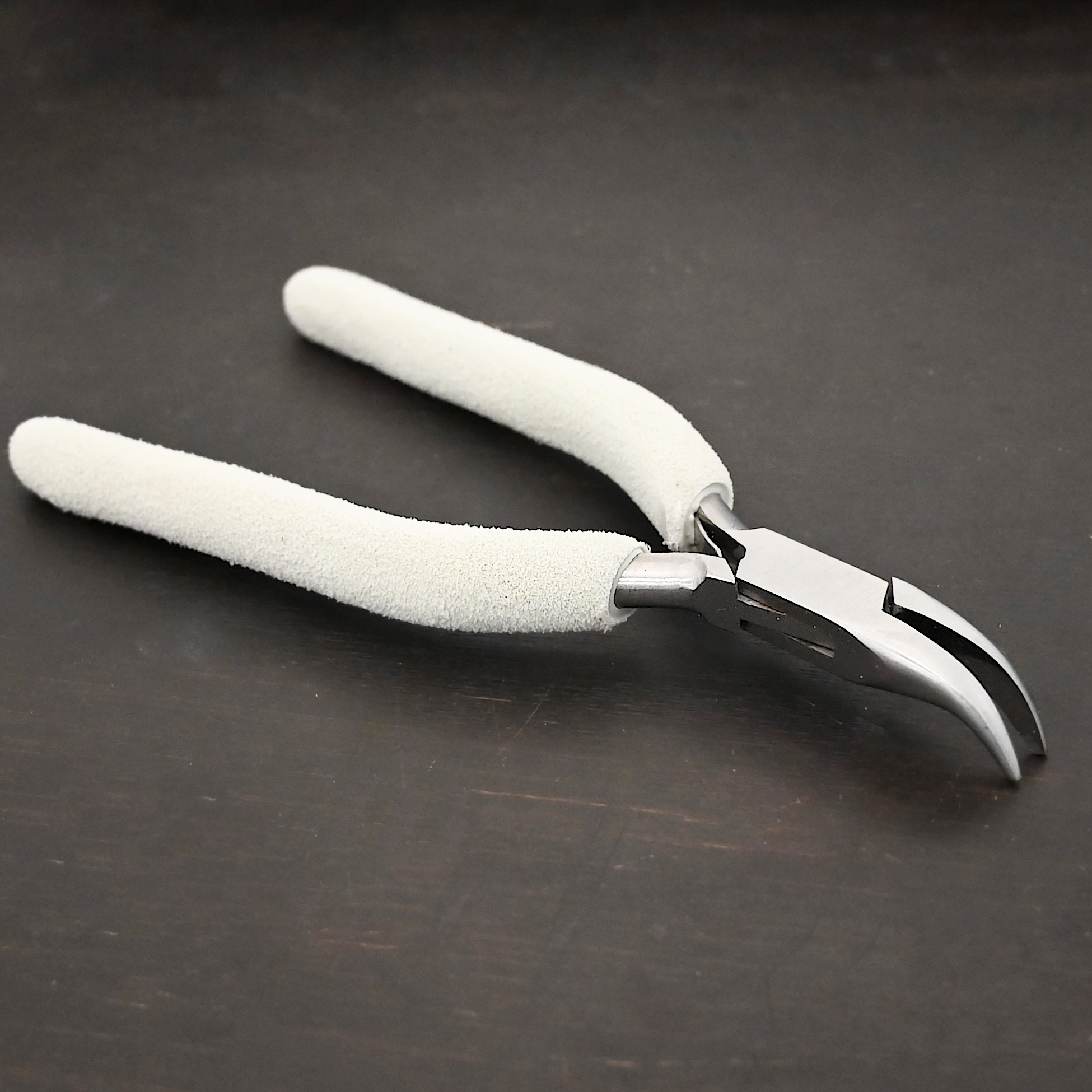 Curved Pliers included in kit - stainless steel and white foam handle shown on dark background