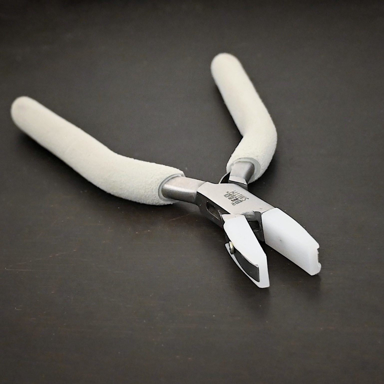 Nylon Jaw Pliers included in kit - stainless steel and white foam handle shown on dark background