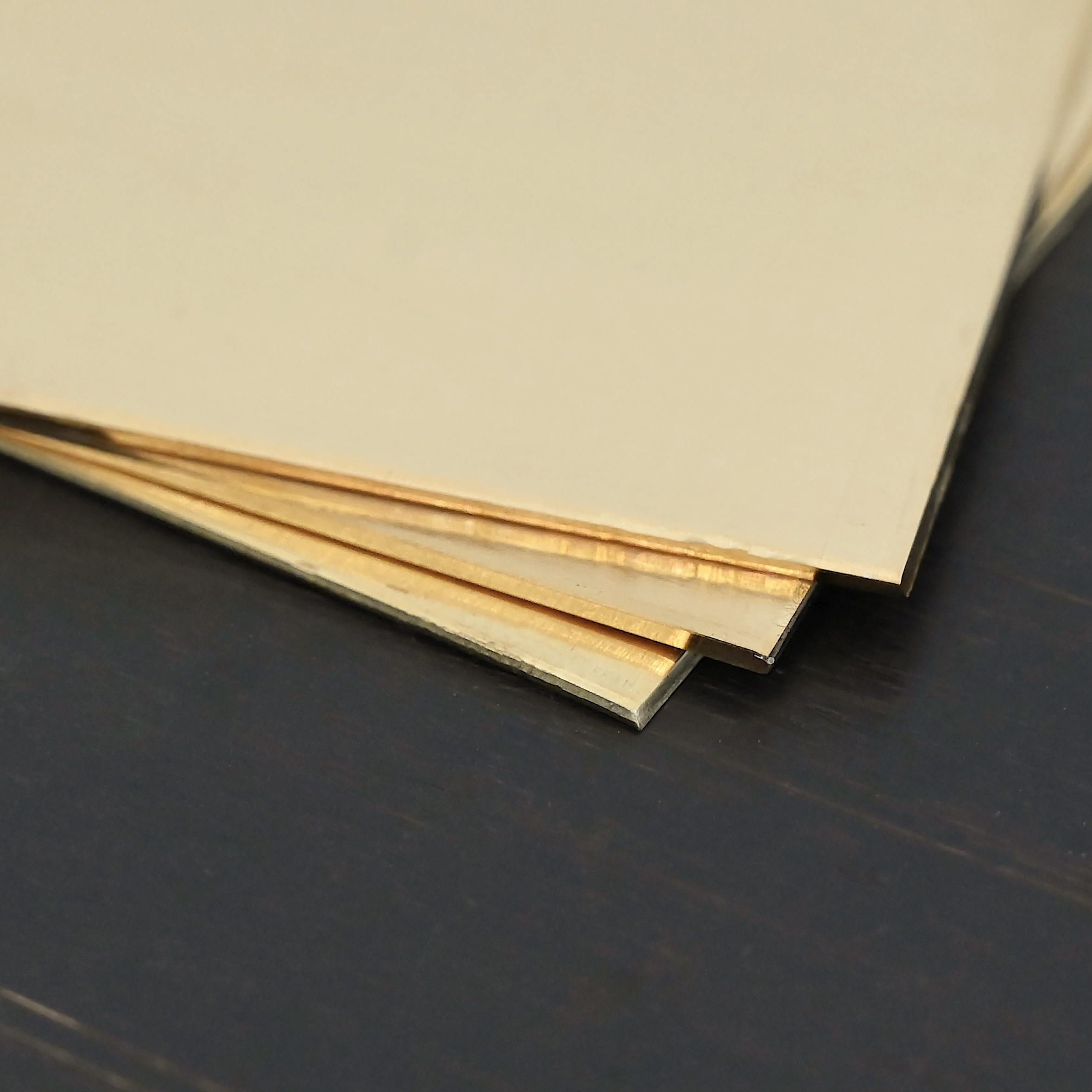 3- 3x3" brass square sheets shown on dark background