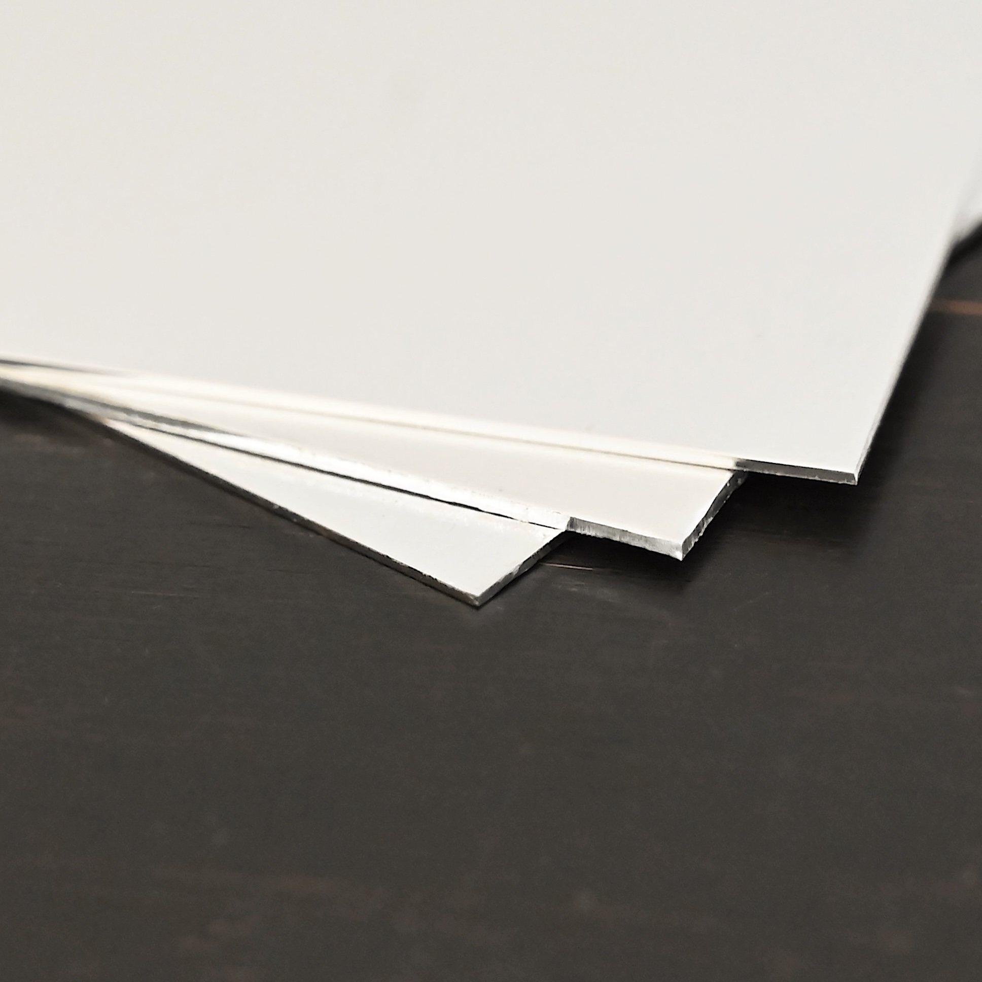 3- silver square sheets shown on dark background