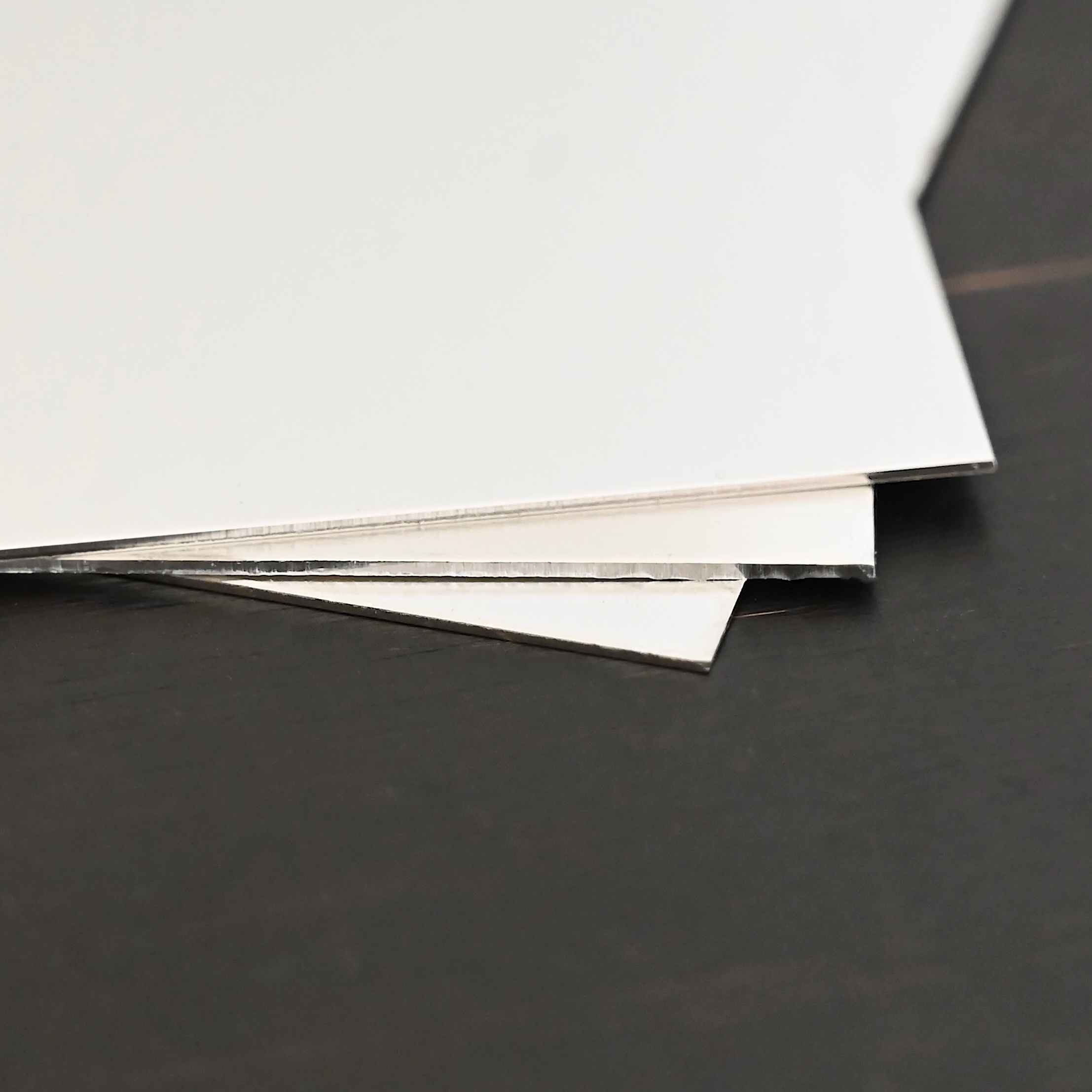 3- silver square sheets shown on dark background