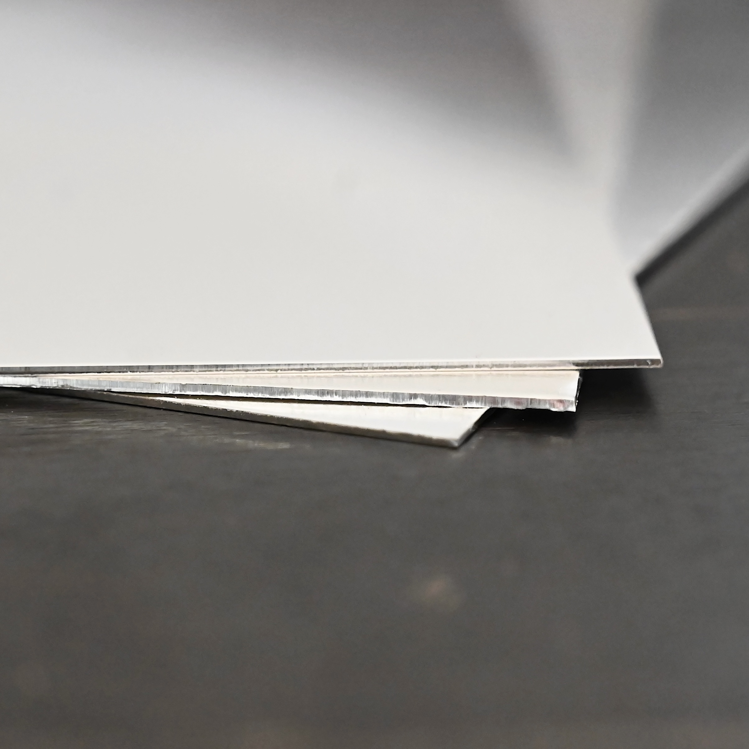 3- silver square sheets shown on dark background