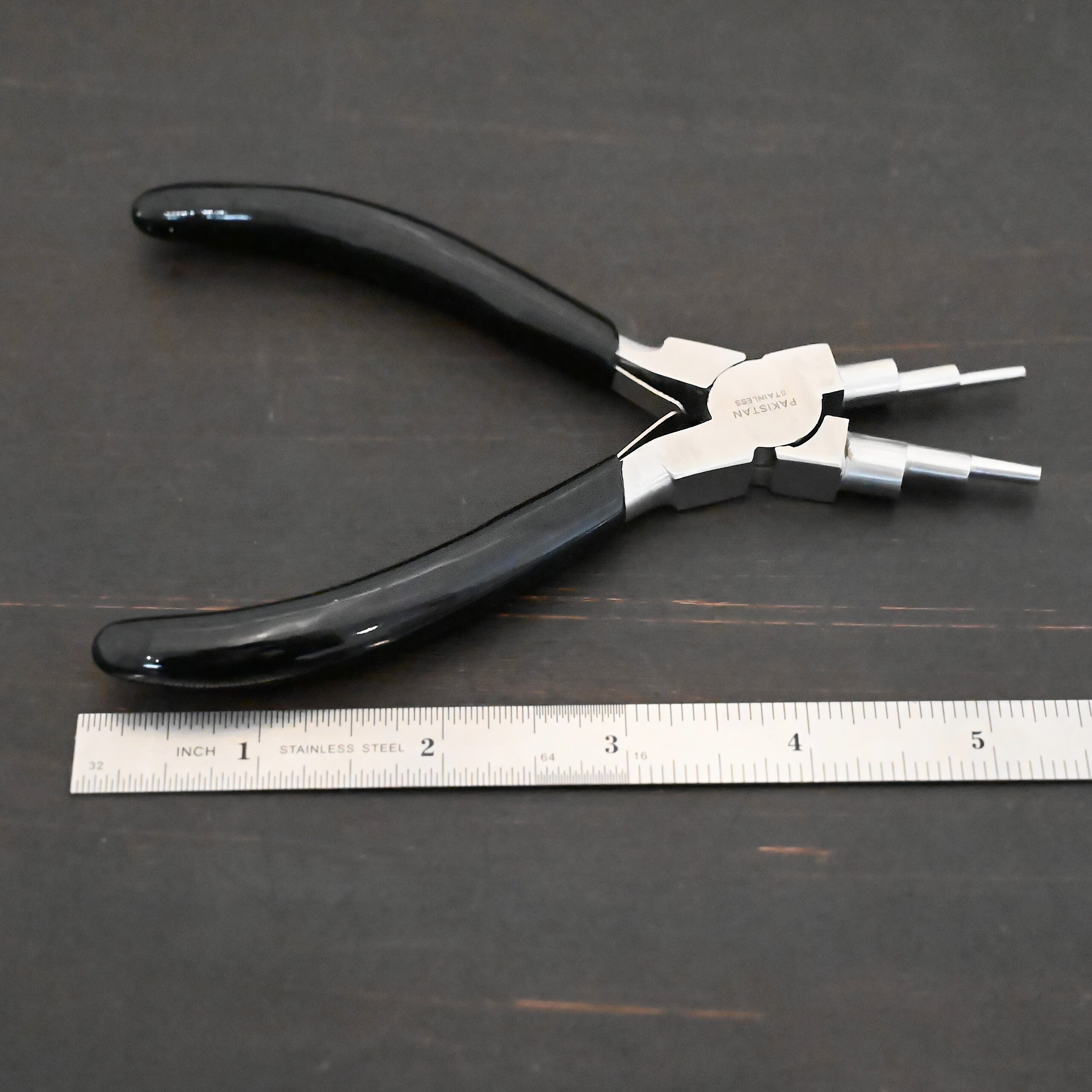 Double Stepped Mandrel Pliers - Black rubber handle shown next to ruler