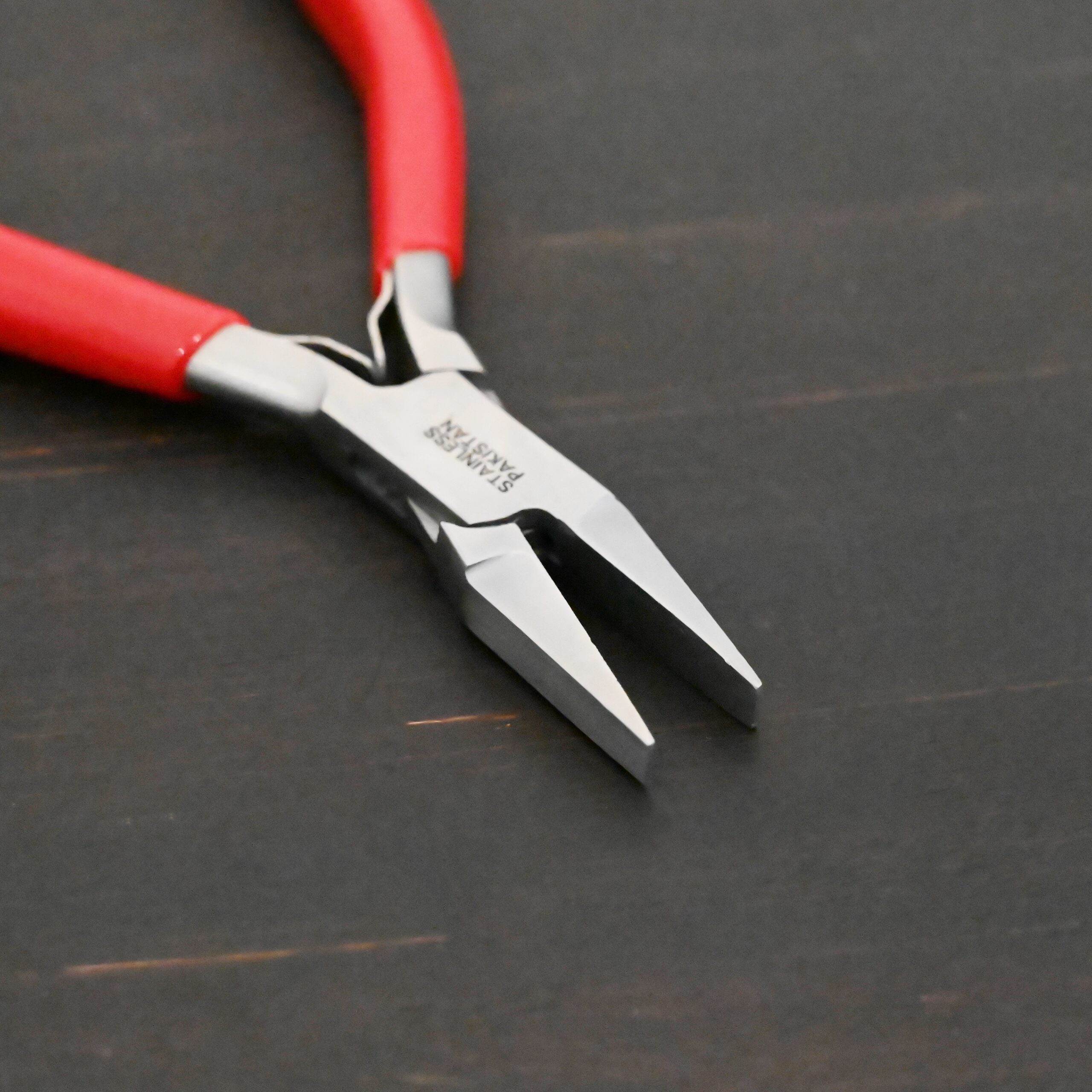 Flat Jaw Pliers - Red rubber handle shown on dark background