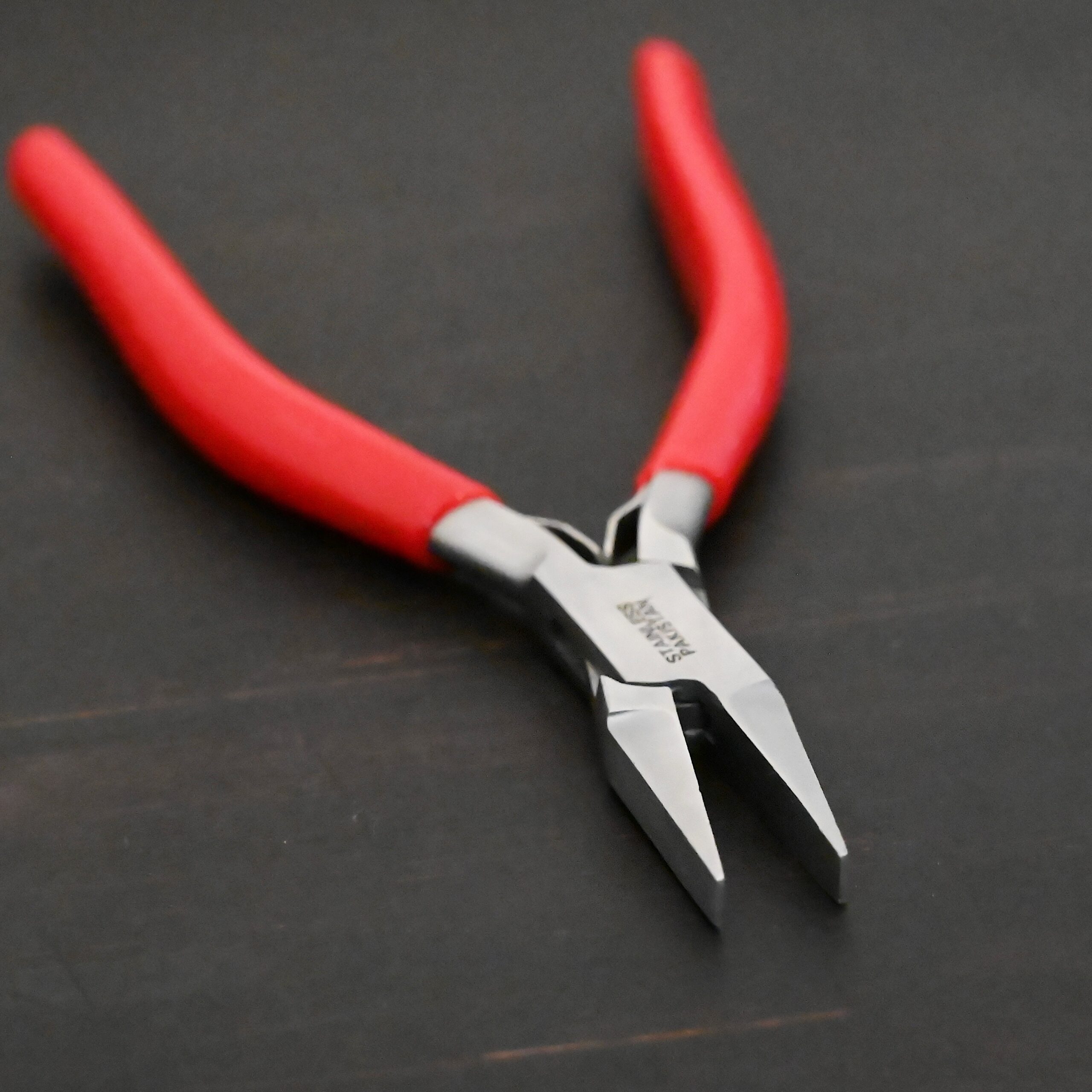 Flat Jaw Pliers - Red rubber handle shown on dark background