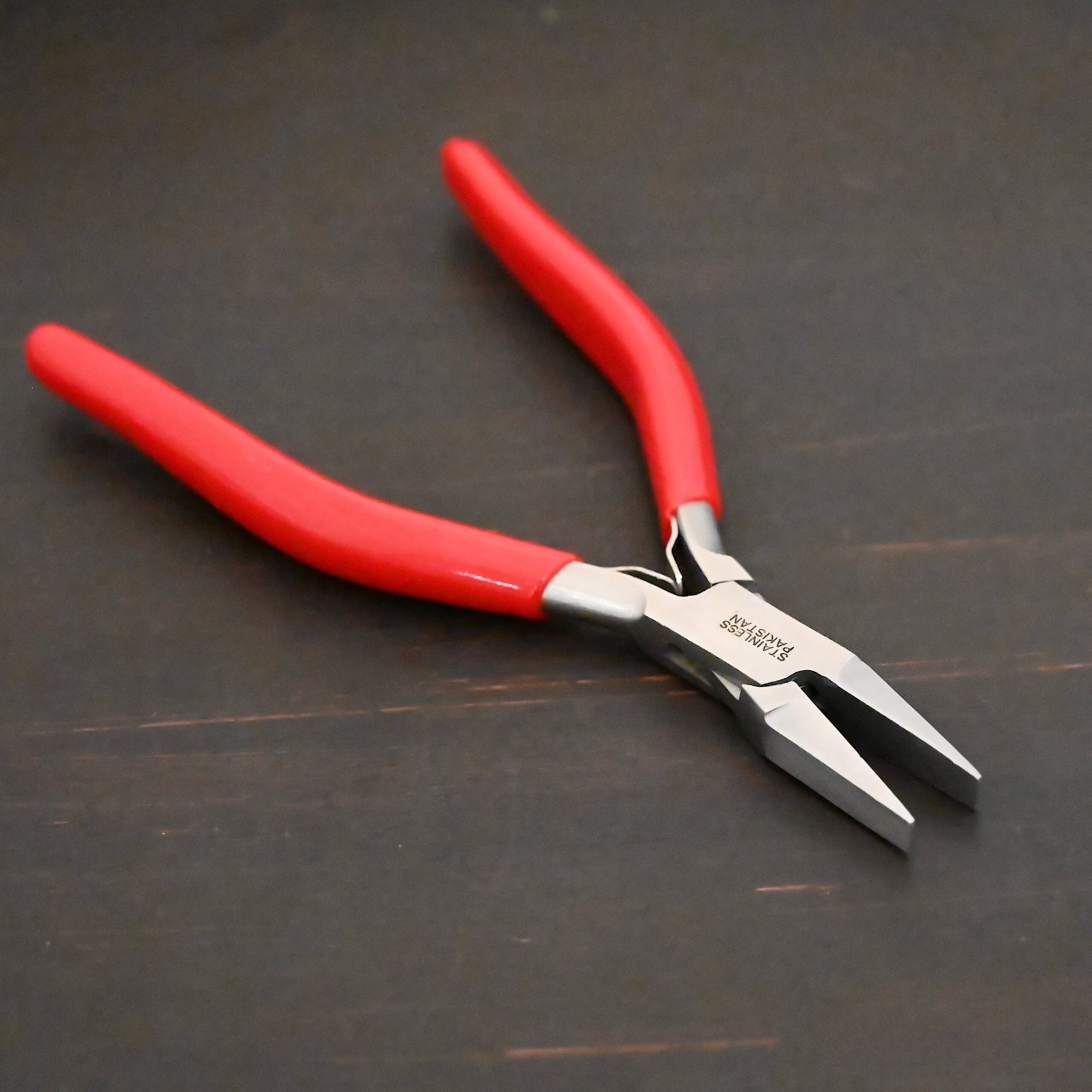 Flat Jaw Pliers - Red rubber handle shown on dark background