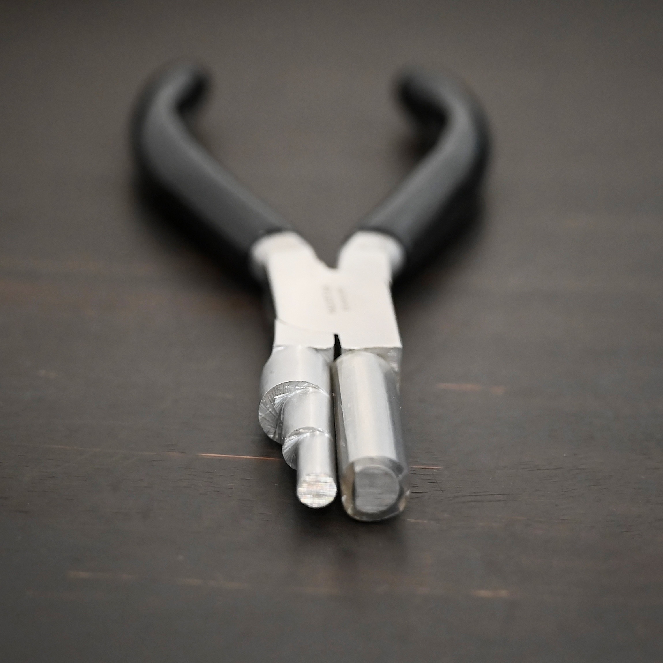 Large stepped mandrel pliers - black rubber handle shown on dark background