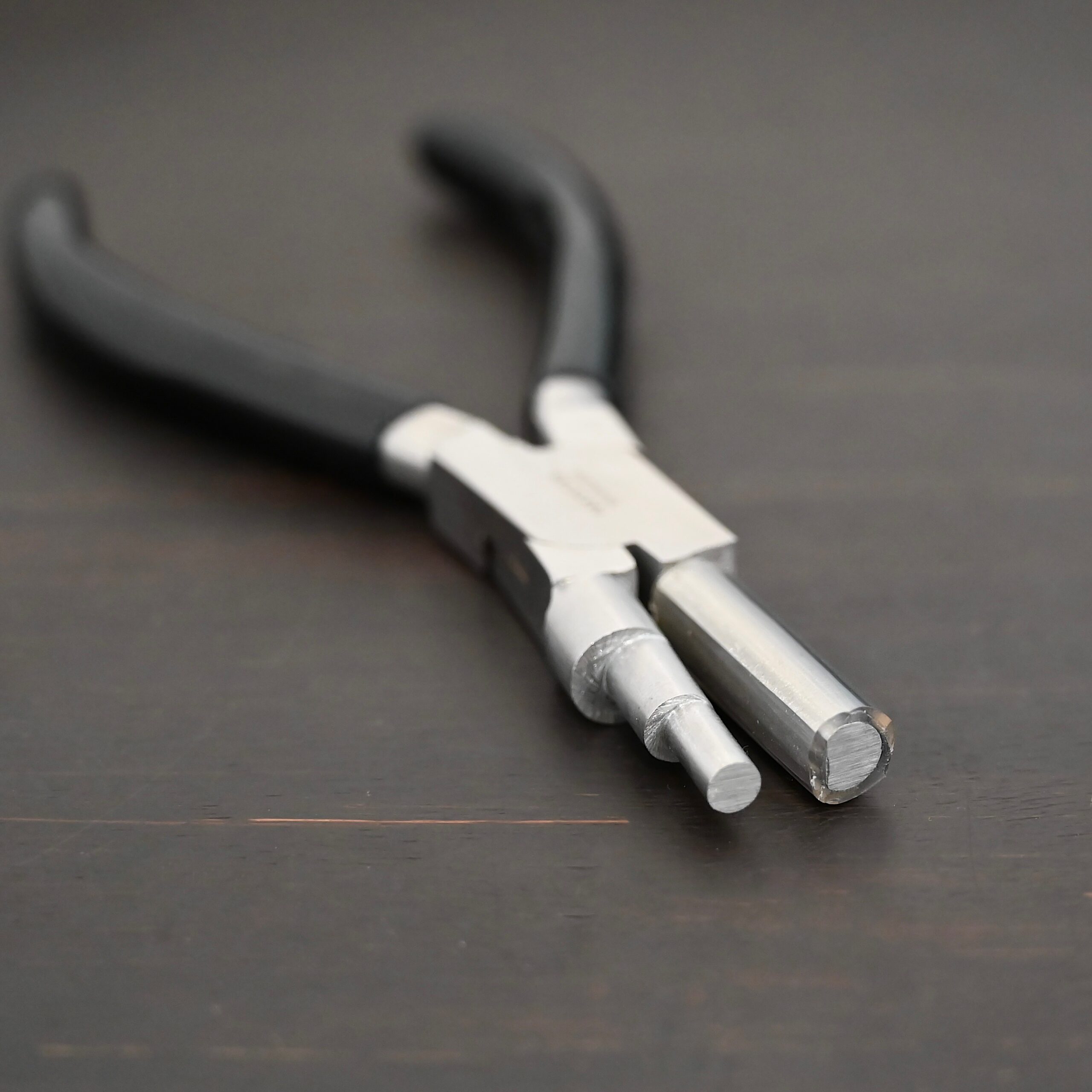 Large stepped mandrel pliers - black rubber handle shown on dark background