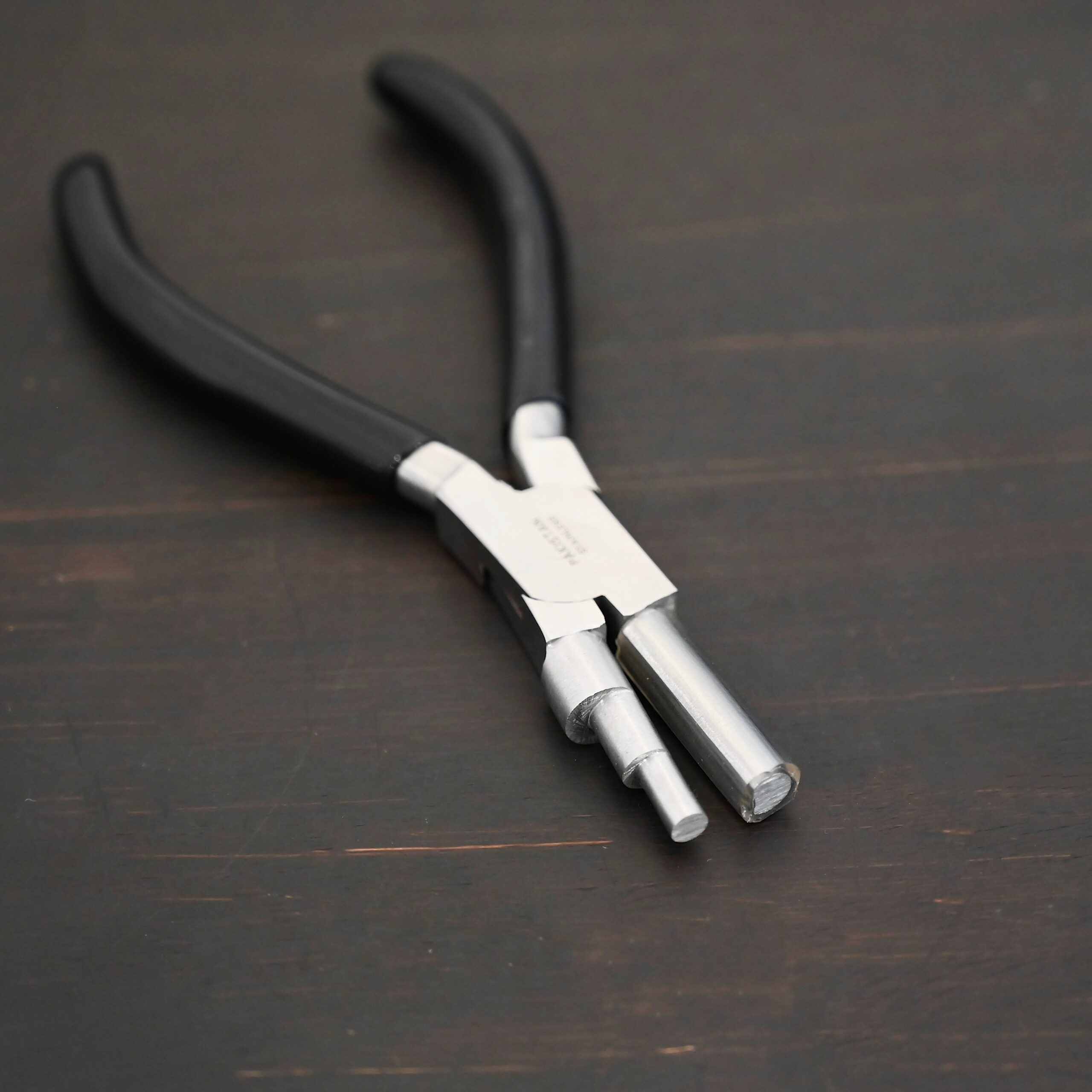 Large stepped mandrel pliers - black rubber handle shown on dark background