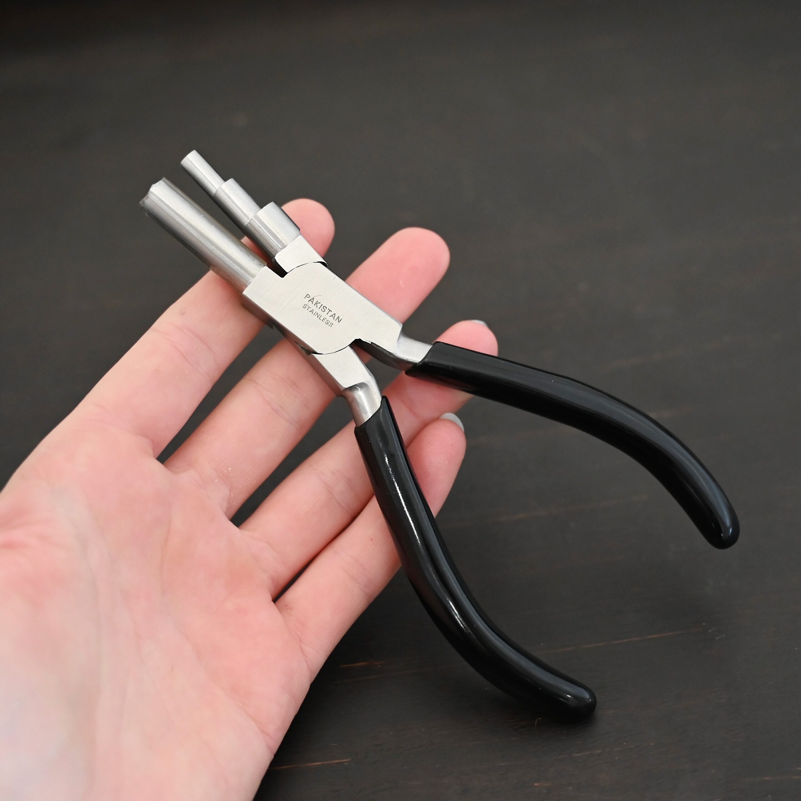 Large stepped mandrel pliers - black rubber handle shown in hand