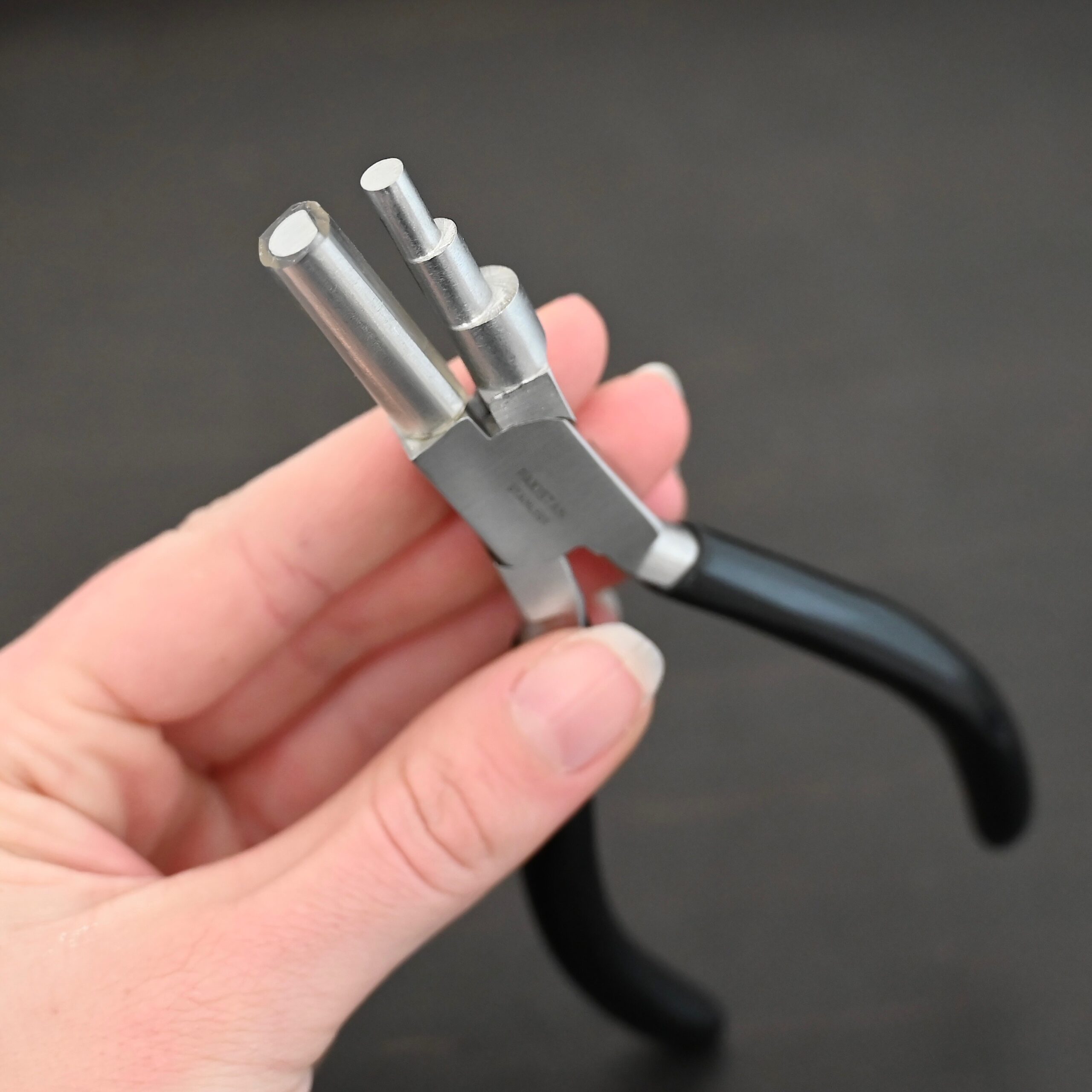 Large stepped mandrel pliers - black rubber handle shown in hand