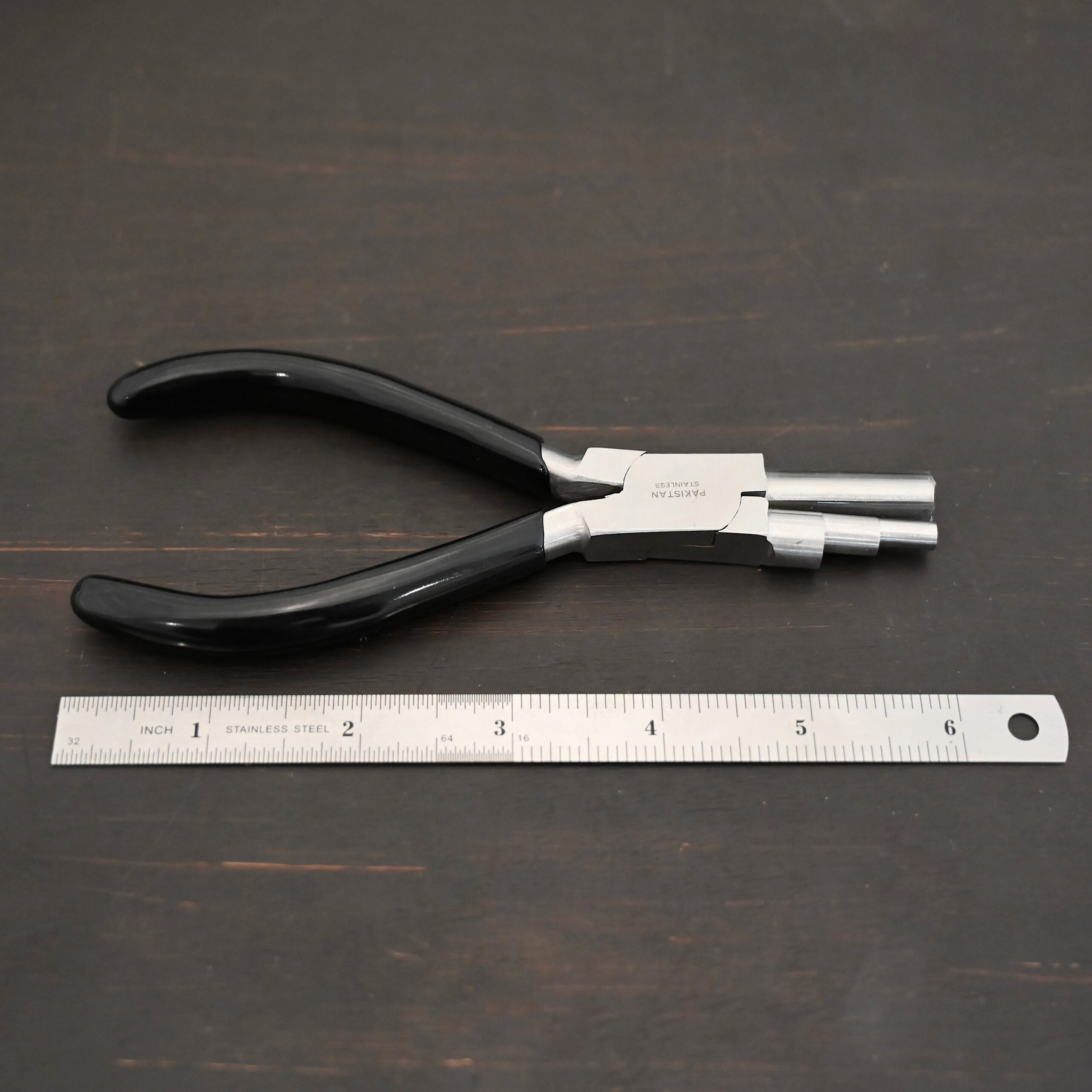 Large stepped mandrel pliers - black rubber handle shown by ruler