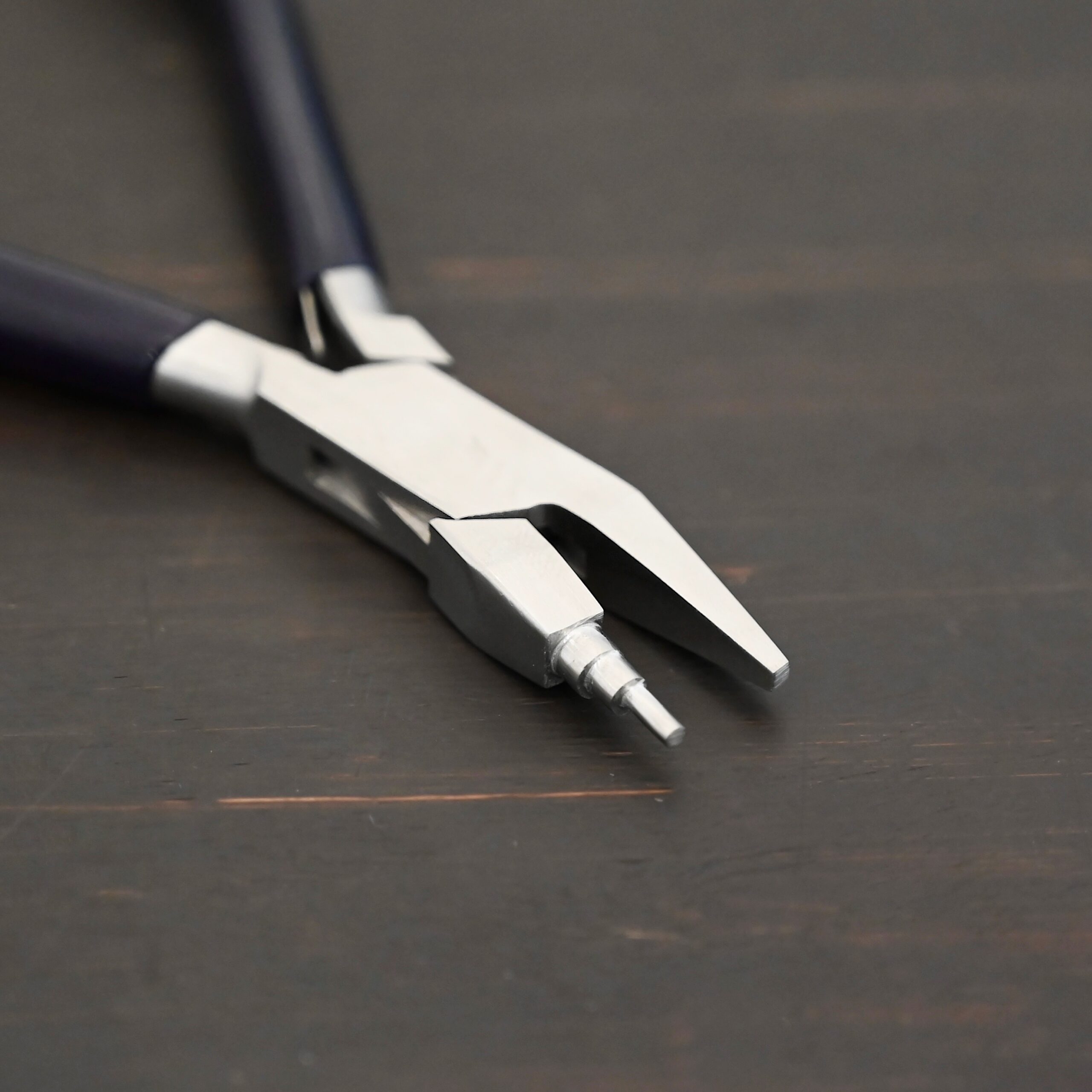 Sawyer - Small Stepped Mandrel Pliers Small Stepped Mandrel pliers - Black rubber handle shown on dark background