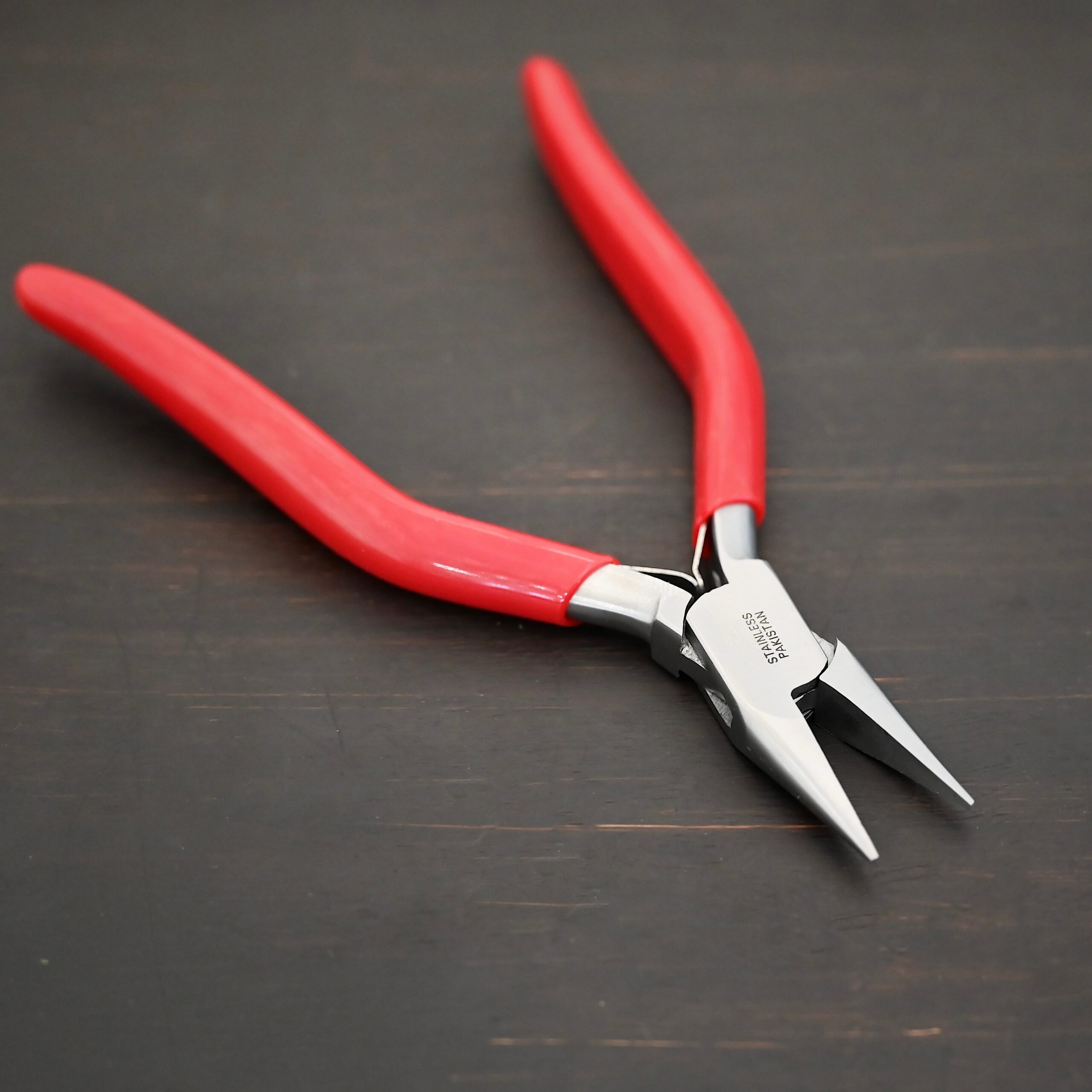 Flat Nosed pliers - Red rubber handle shown on dark background