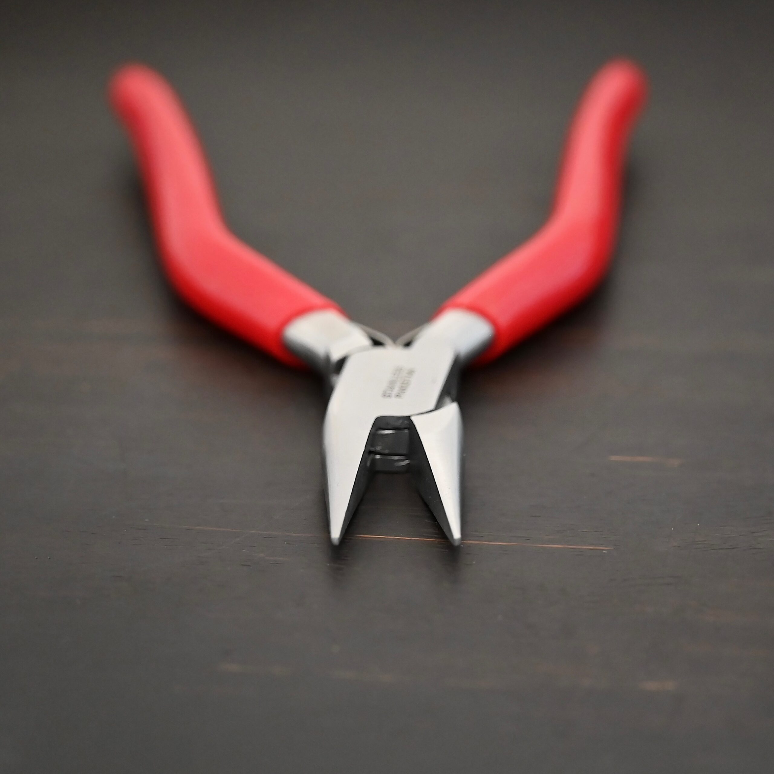 Flat Nosed pliers - Red rubber handle shown on dark background