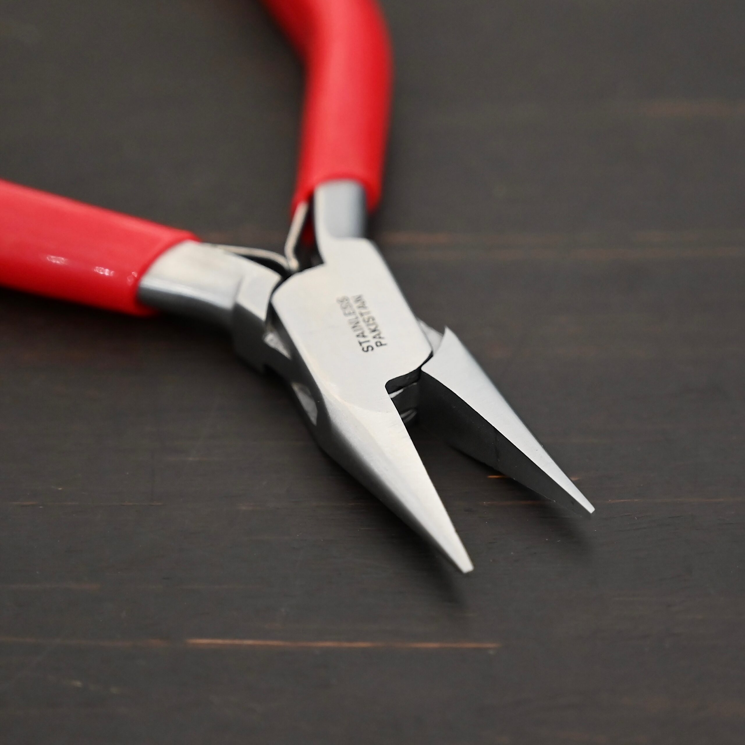 Flat Nosed pliers - Red rubber handle shown on dark background