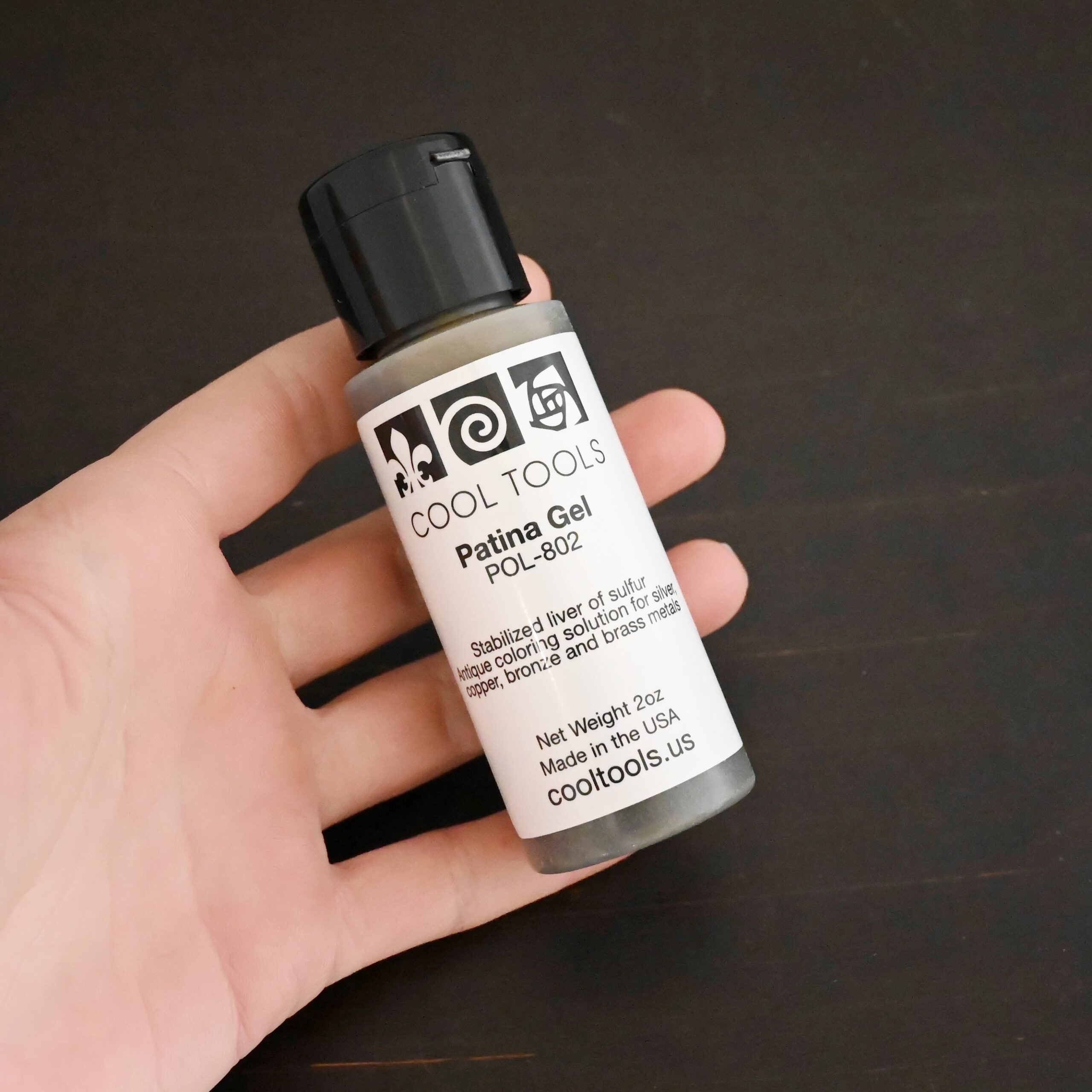 Gel Patina 2oz bottle with black top shown in hand