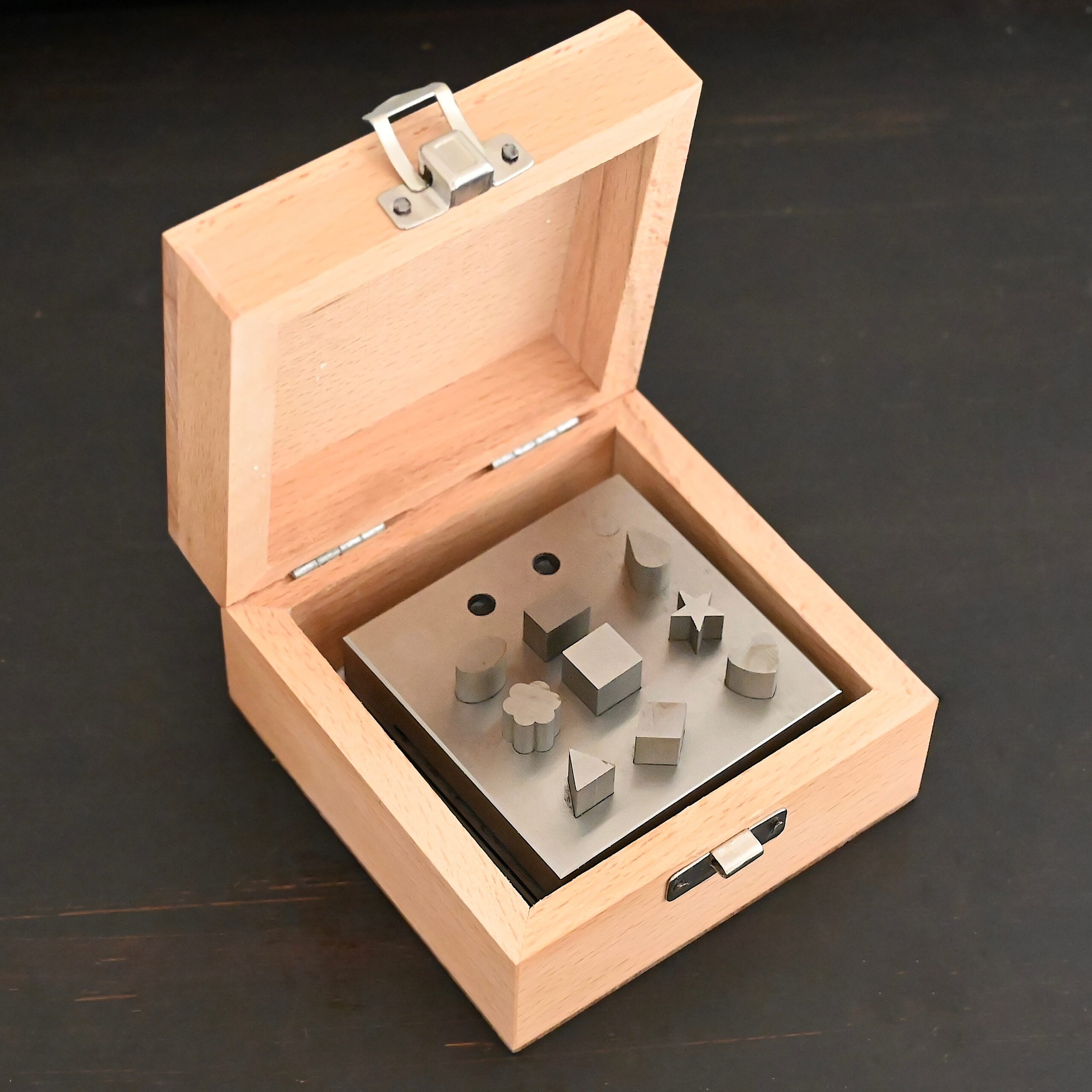 Stainless Steel Disc Cutter Showing all punches in wooden box on dark background