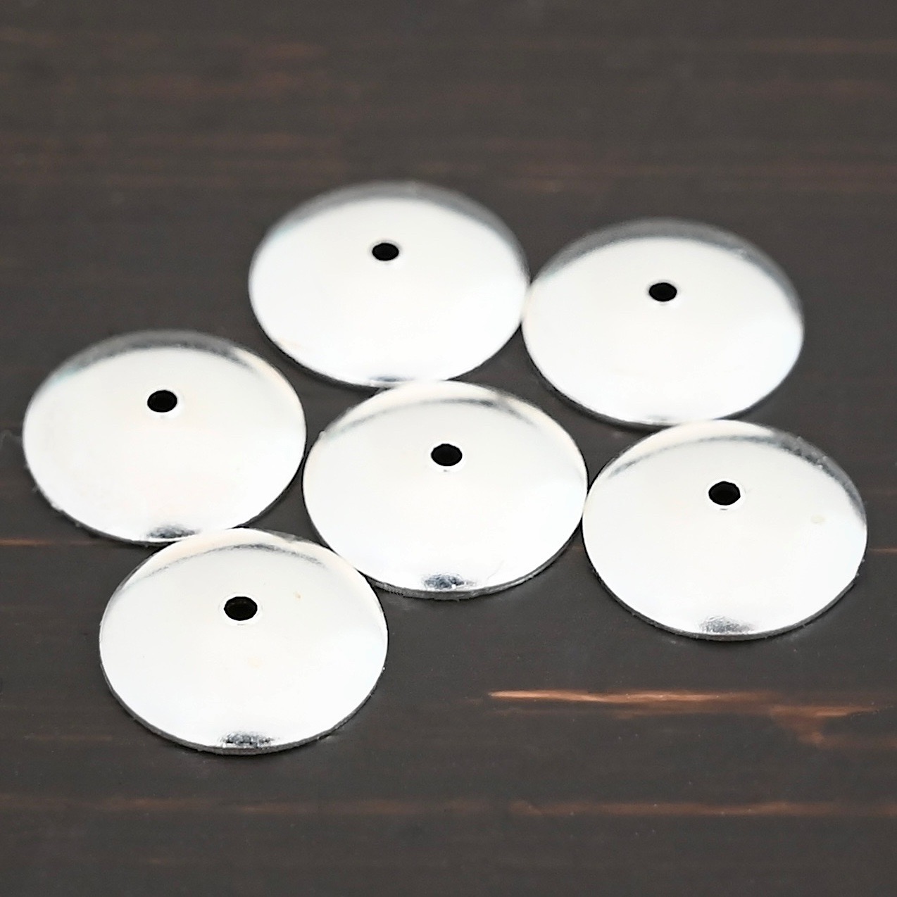 Silver shiny bead caps shown on dark background