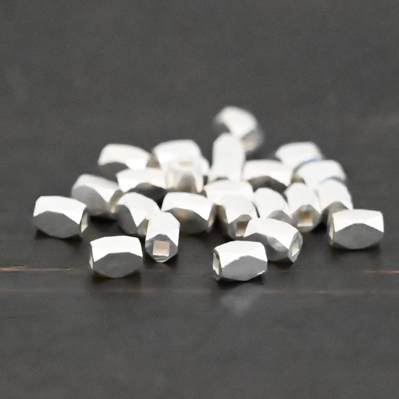 Silver shiny rectangle beads shown on dark background