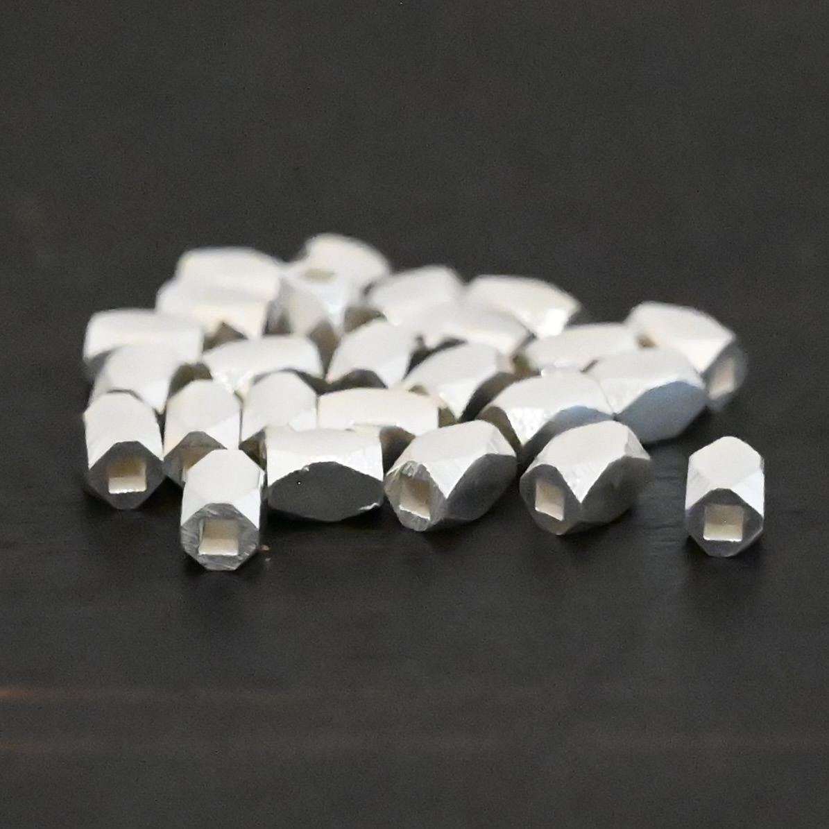 Silver shiny rectangle beads shown on dark background