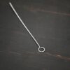 Silver shiny eye pin on dark background