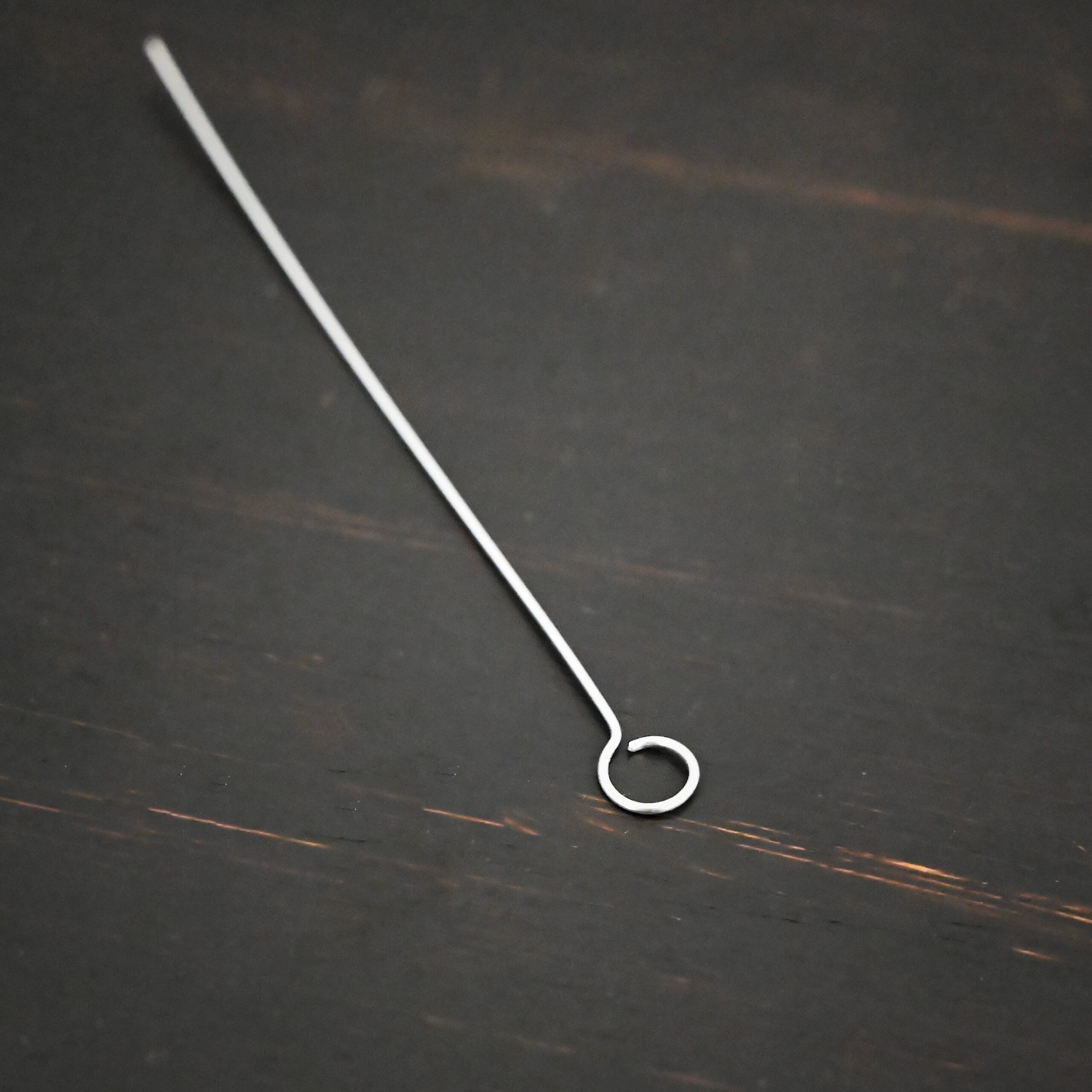 Silver shiny eye pin on dark background