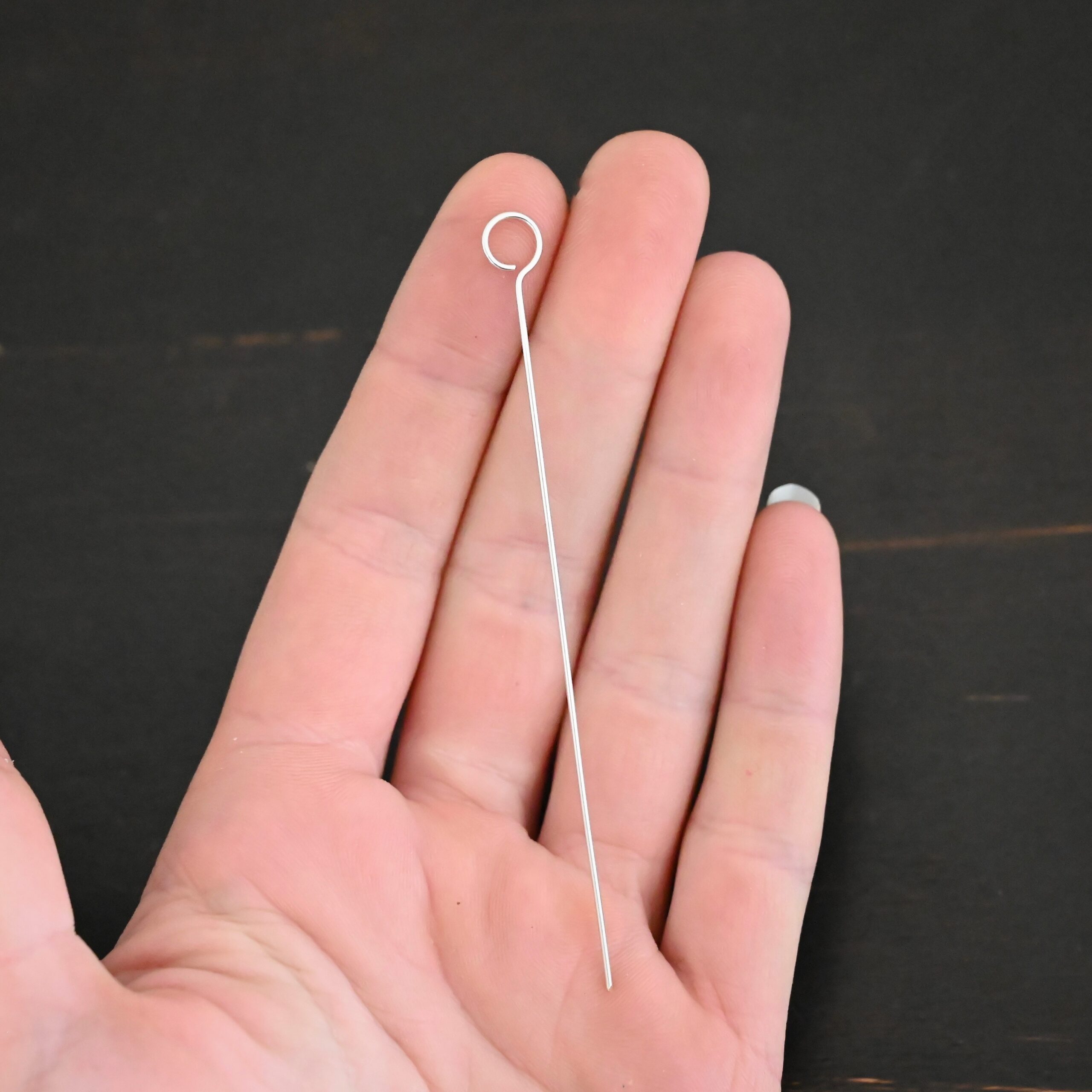 Silver shiny eye pin shown in hand