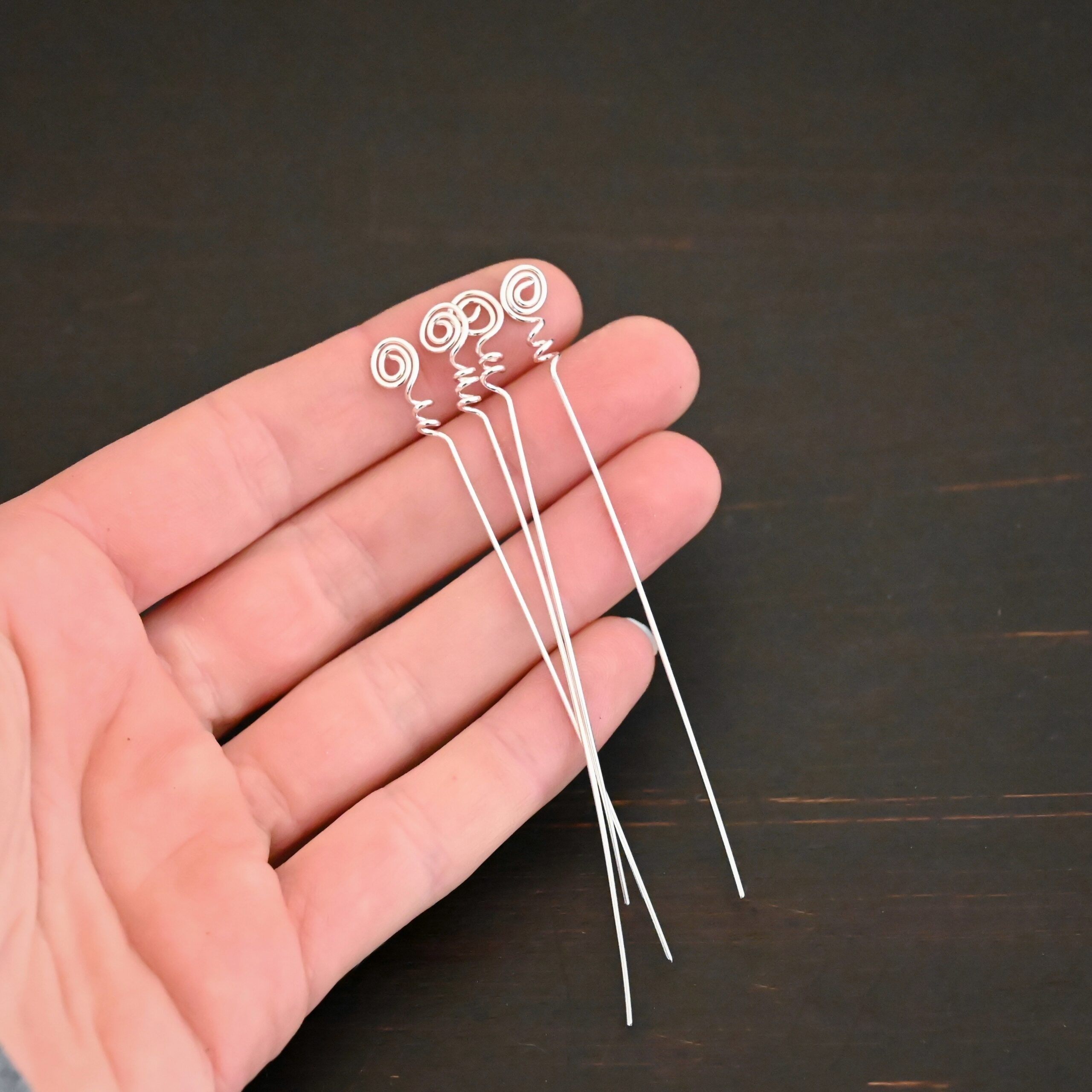 Silver shiny swirl headpin shown in hand
