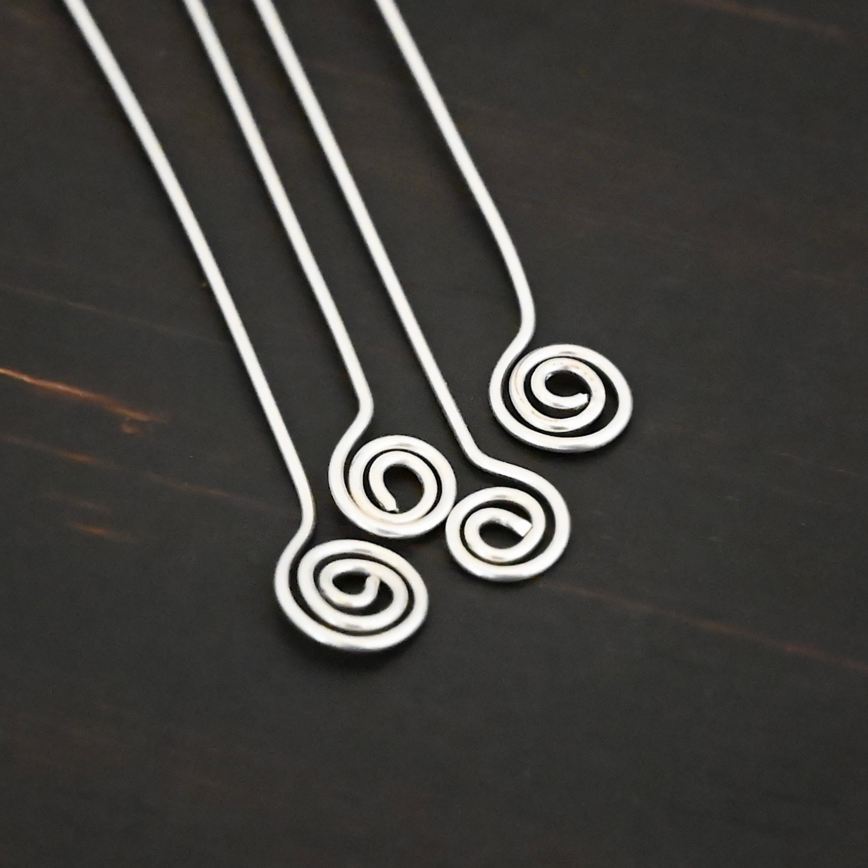 Silver Shiny Swirl headpin shown on dark background