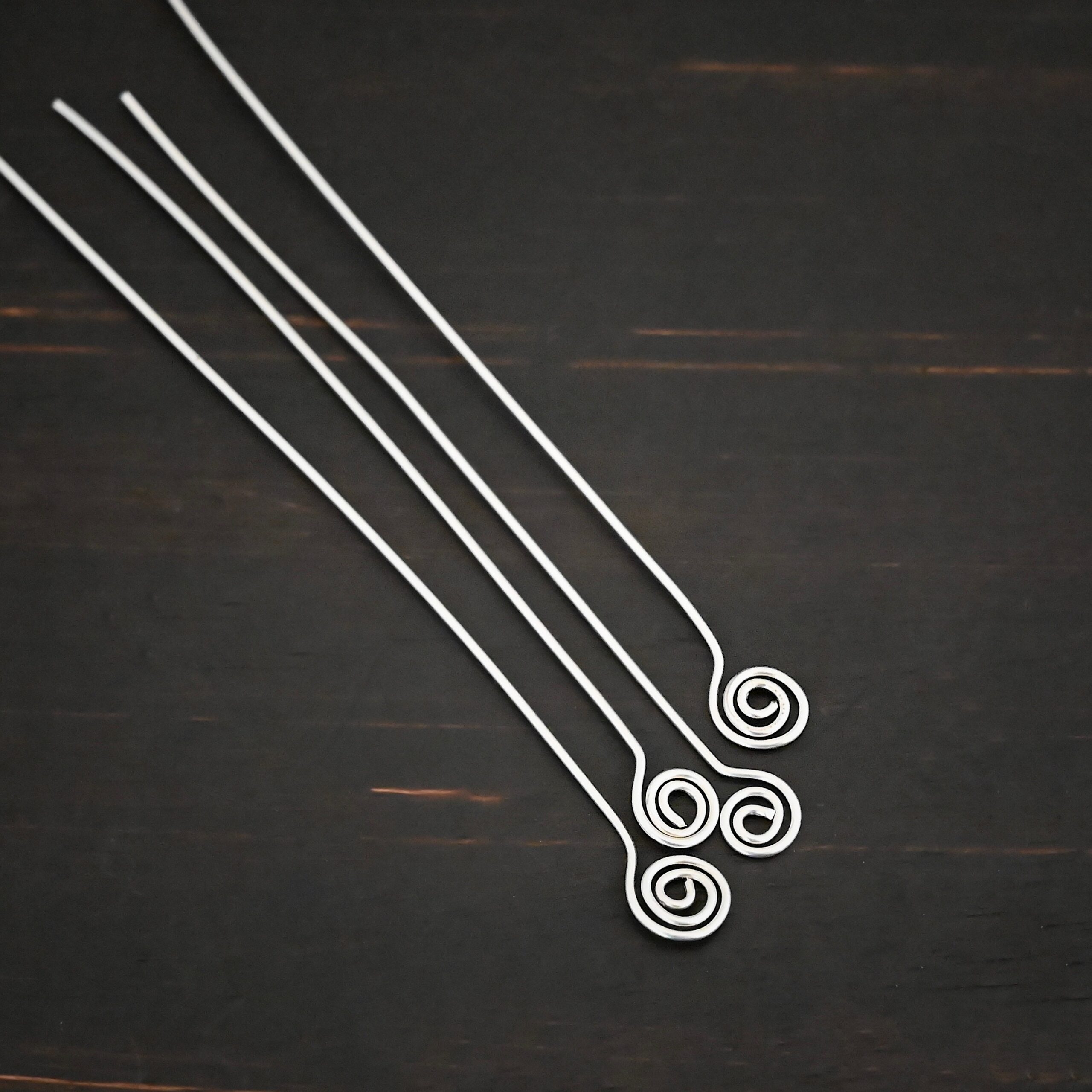 Silver Shiny Swirl headpin shown on dark background