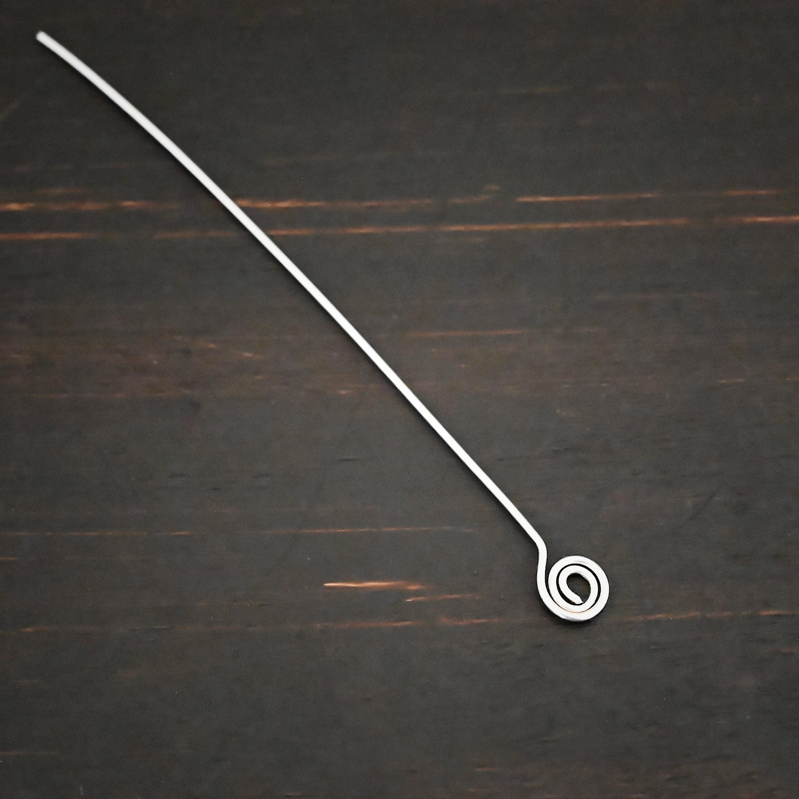 Silver Shiny Swirl headpin shown on dark background