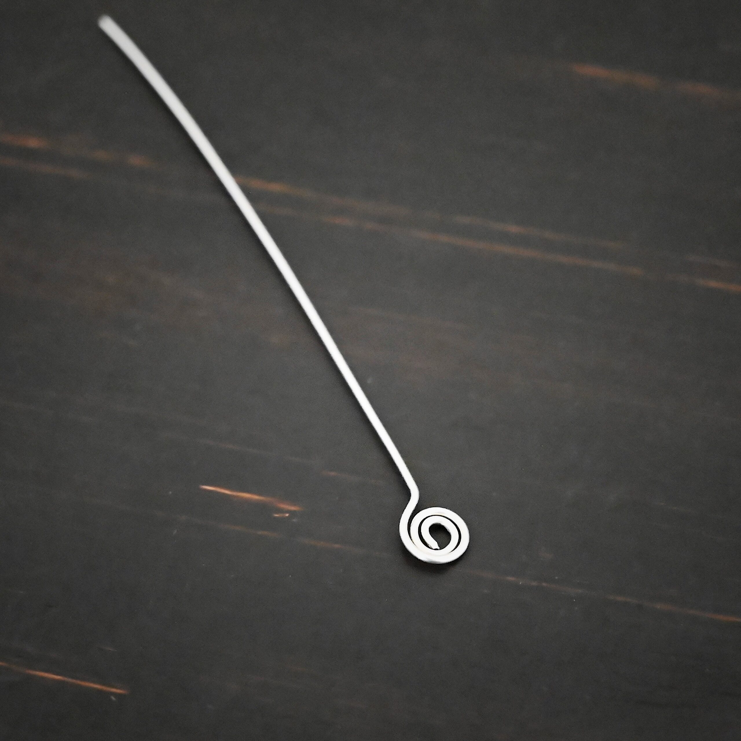 Silver Shiny Swirl headpin shown on dark background