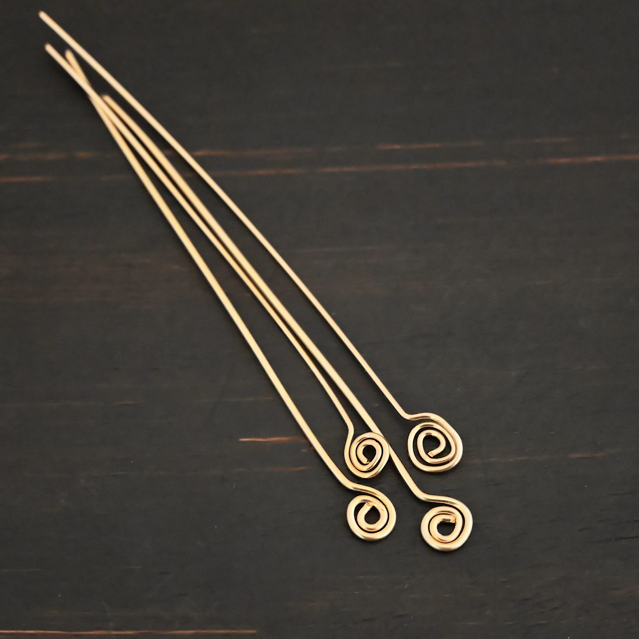 Gold Filled Swirl headpins shown on dark background