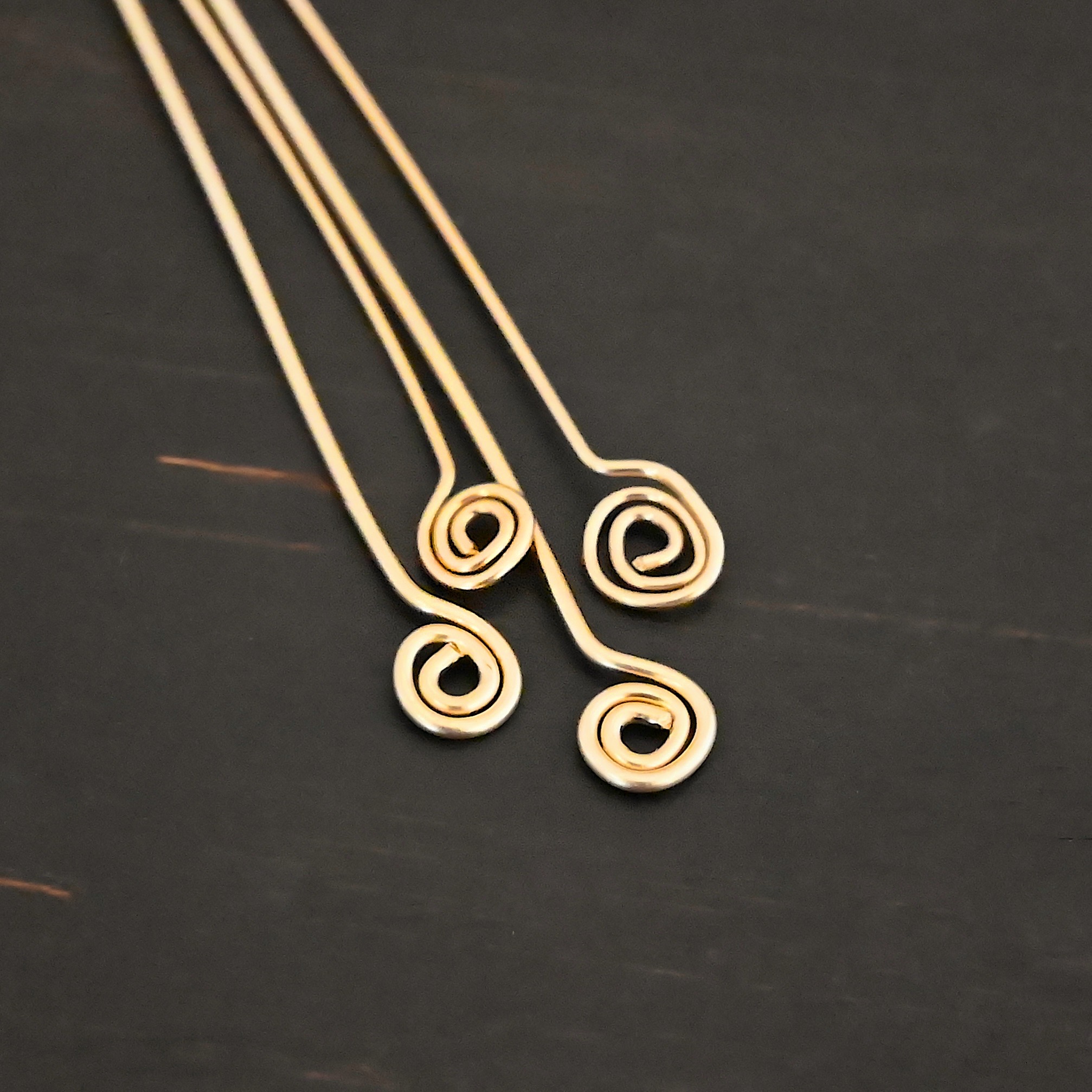 Gold Filled Swirl headpins shown on dark background