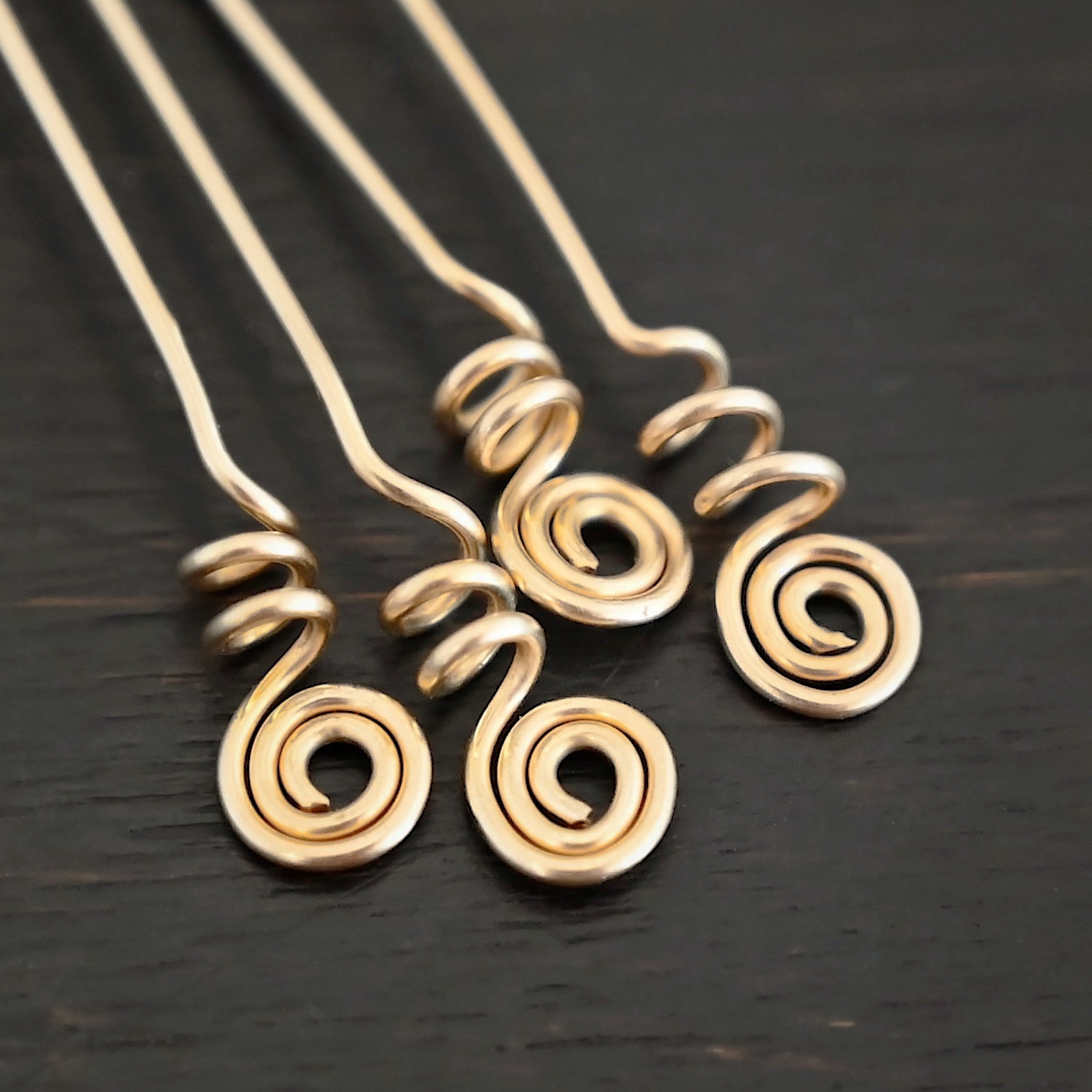 Gold Filled Swirl Headpins shown on dark background