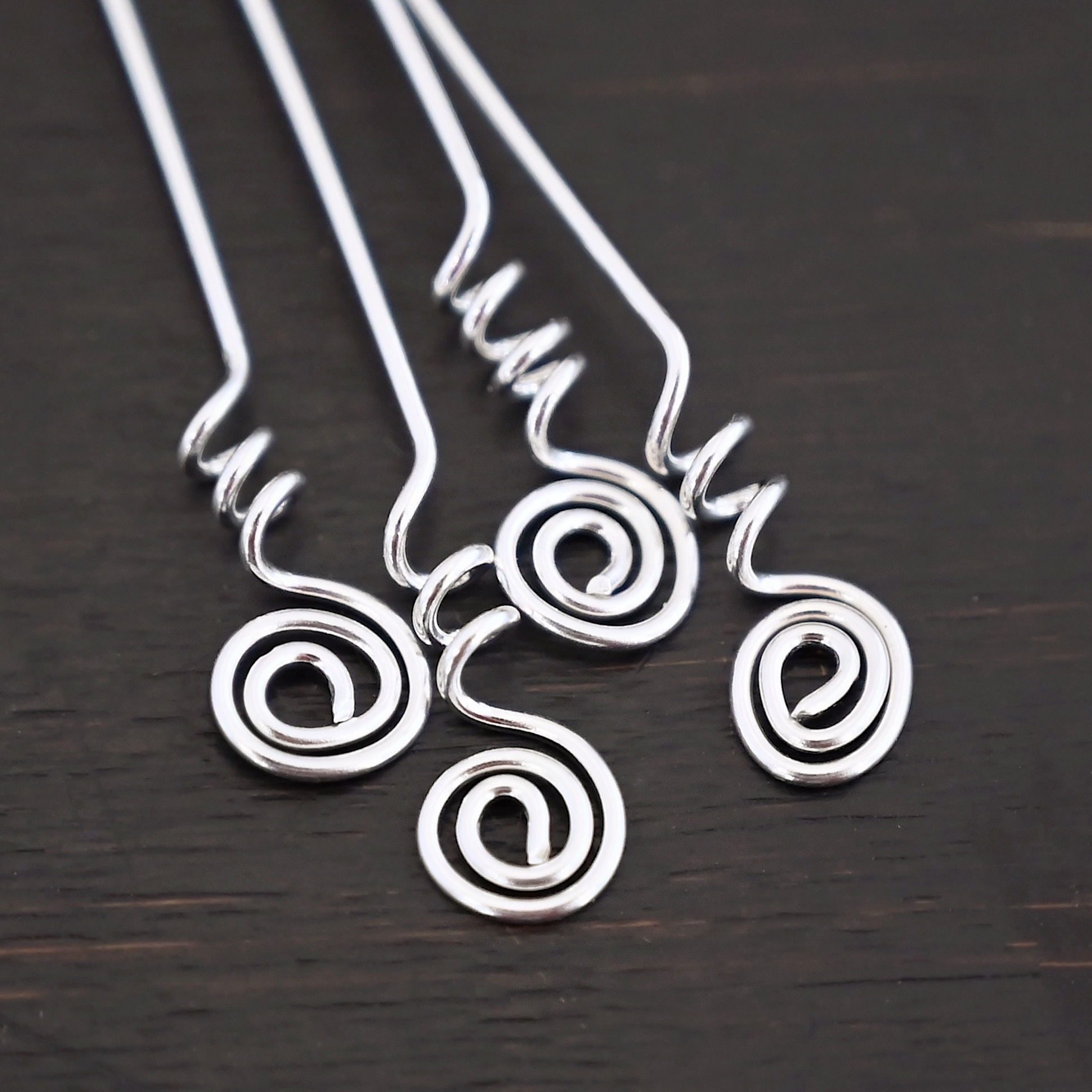 Silver Shiny Swirl Headpins shown on dark background