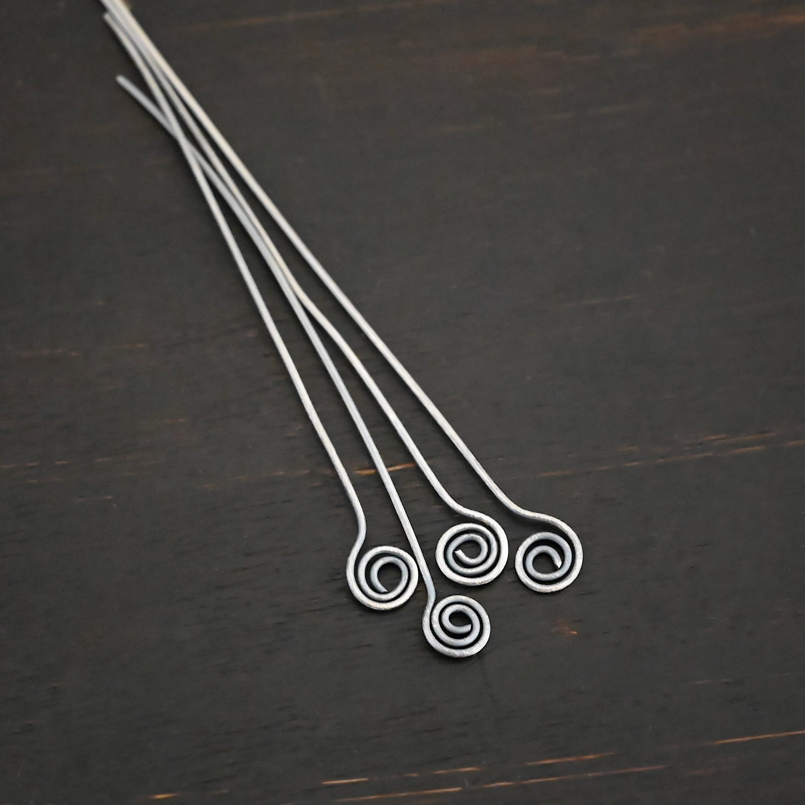 Silver Oxidized Swirl Headpin shown on dark background