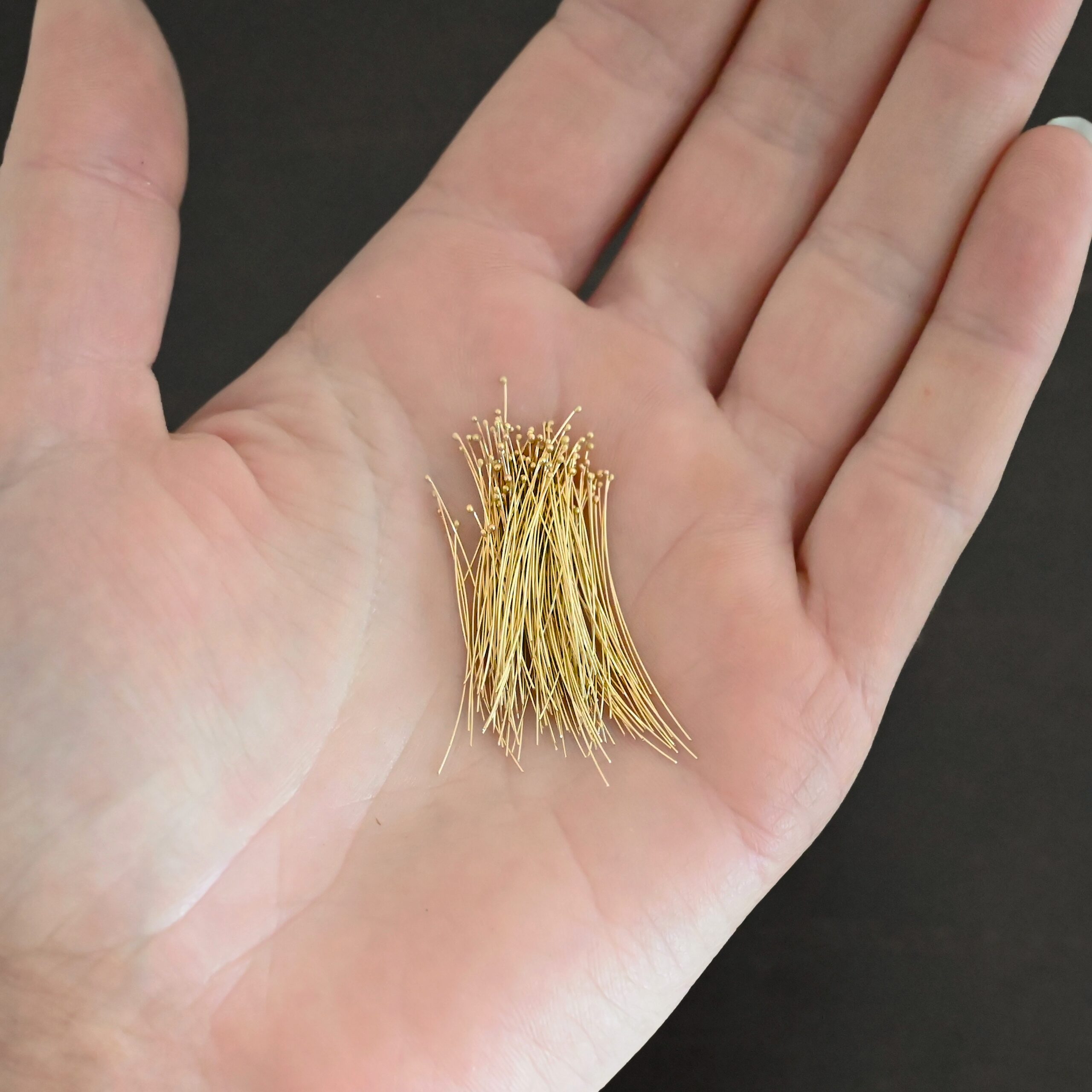 14k gold 30 gauge ball headpins shown in hand