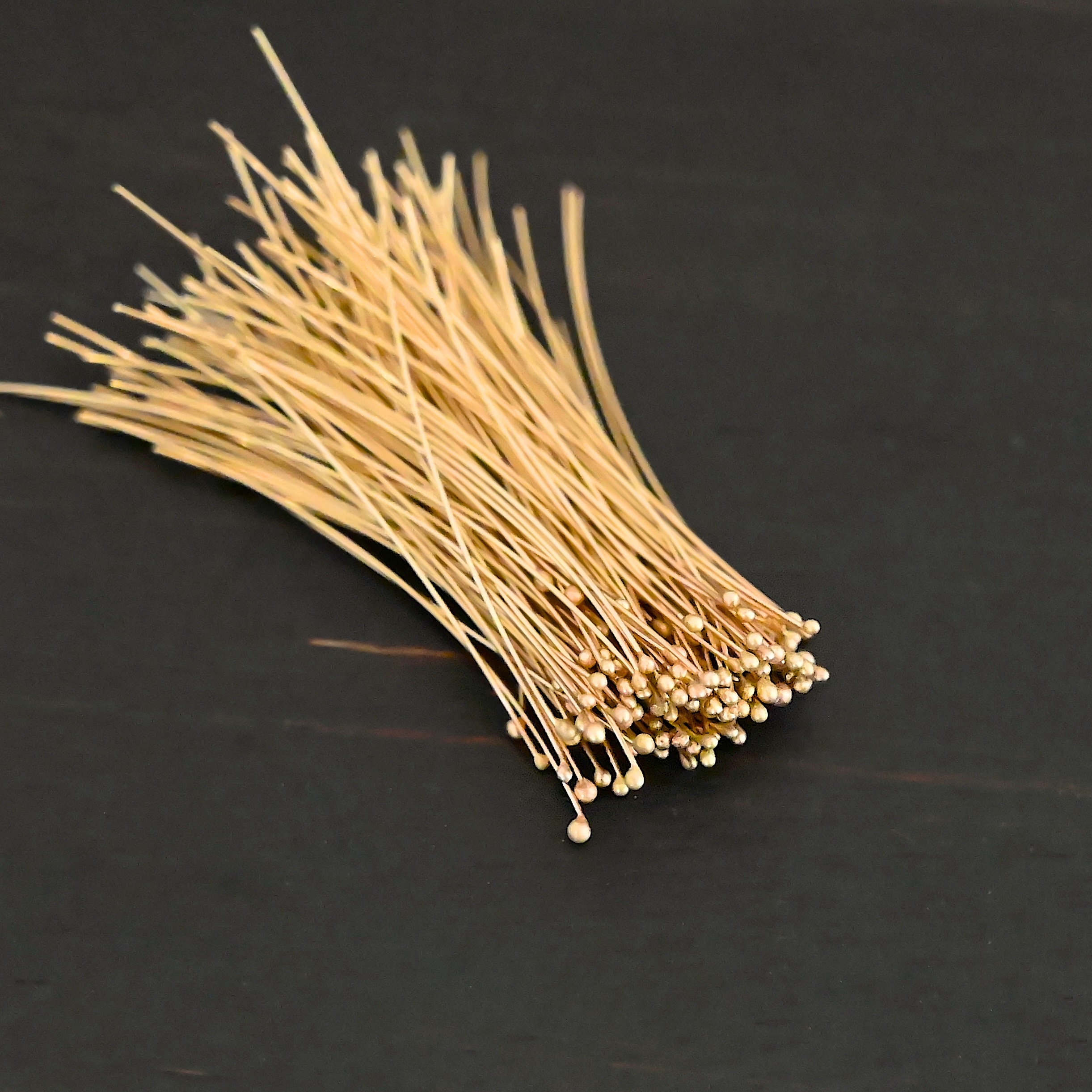 14k gold 30 gauge ball headpins shown on dark background