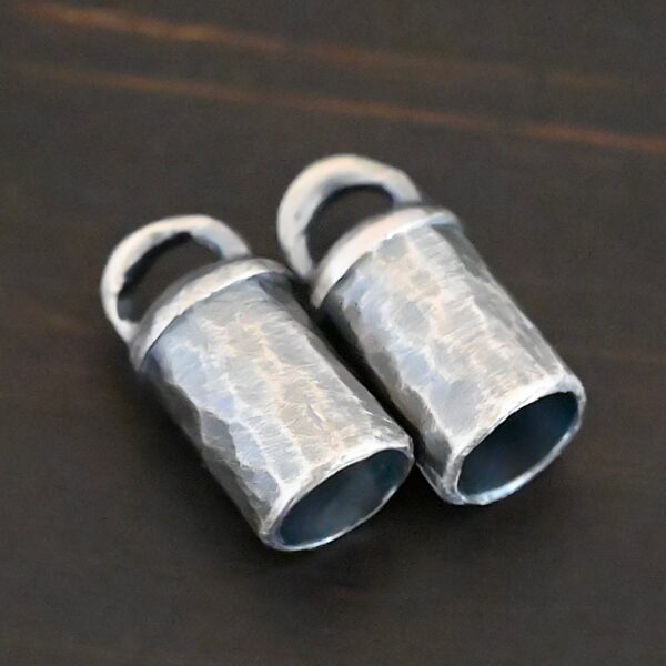 Handmade silver oxidized end caps on dark background