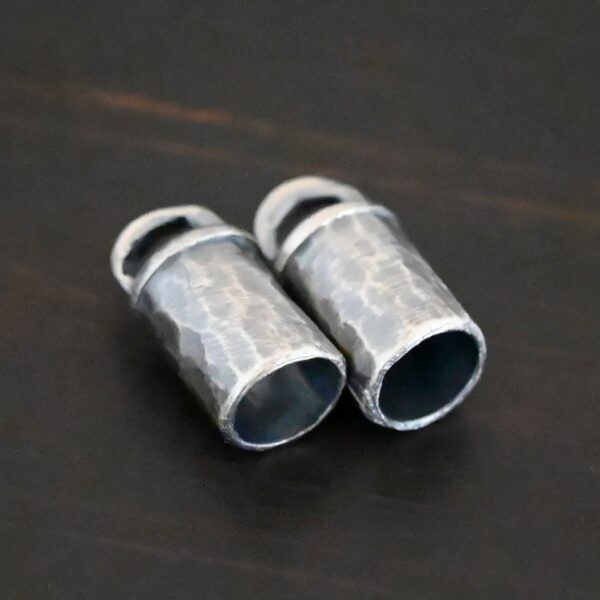 Handmade silver oxidized end caps on dark background